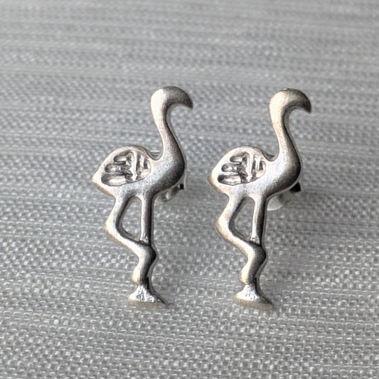 Paar Flamingo Ohrstecker aus mattem 925 Sterling Silber in charakteristischer Einbein-Pose auf hellem Hintergrund.