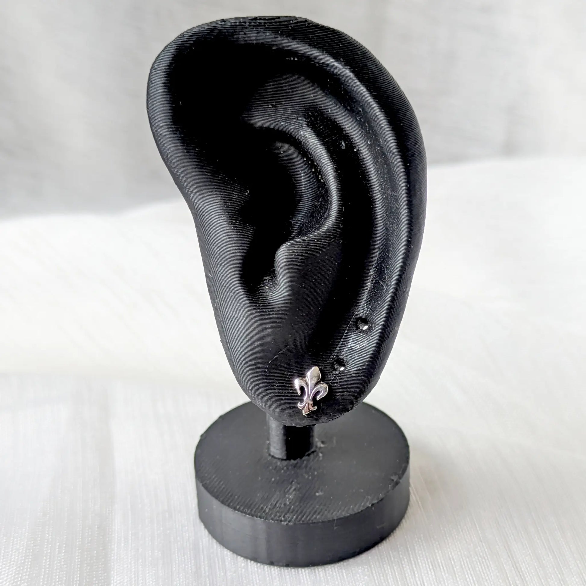 Fleur-de-Lis Ohrstecker aus 925 Silber getragen an einem schwarzen Ohr-Display