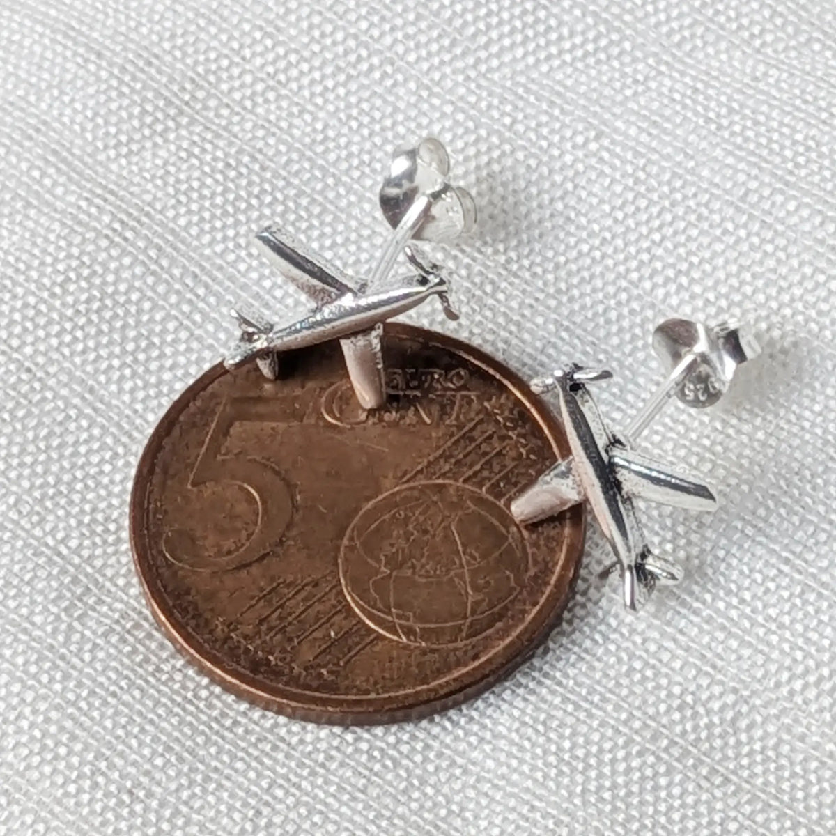 Flugzeug-Ohrstecker aus 925 Silber neben einer 5-Cent-Münze zum Größenvergleich