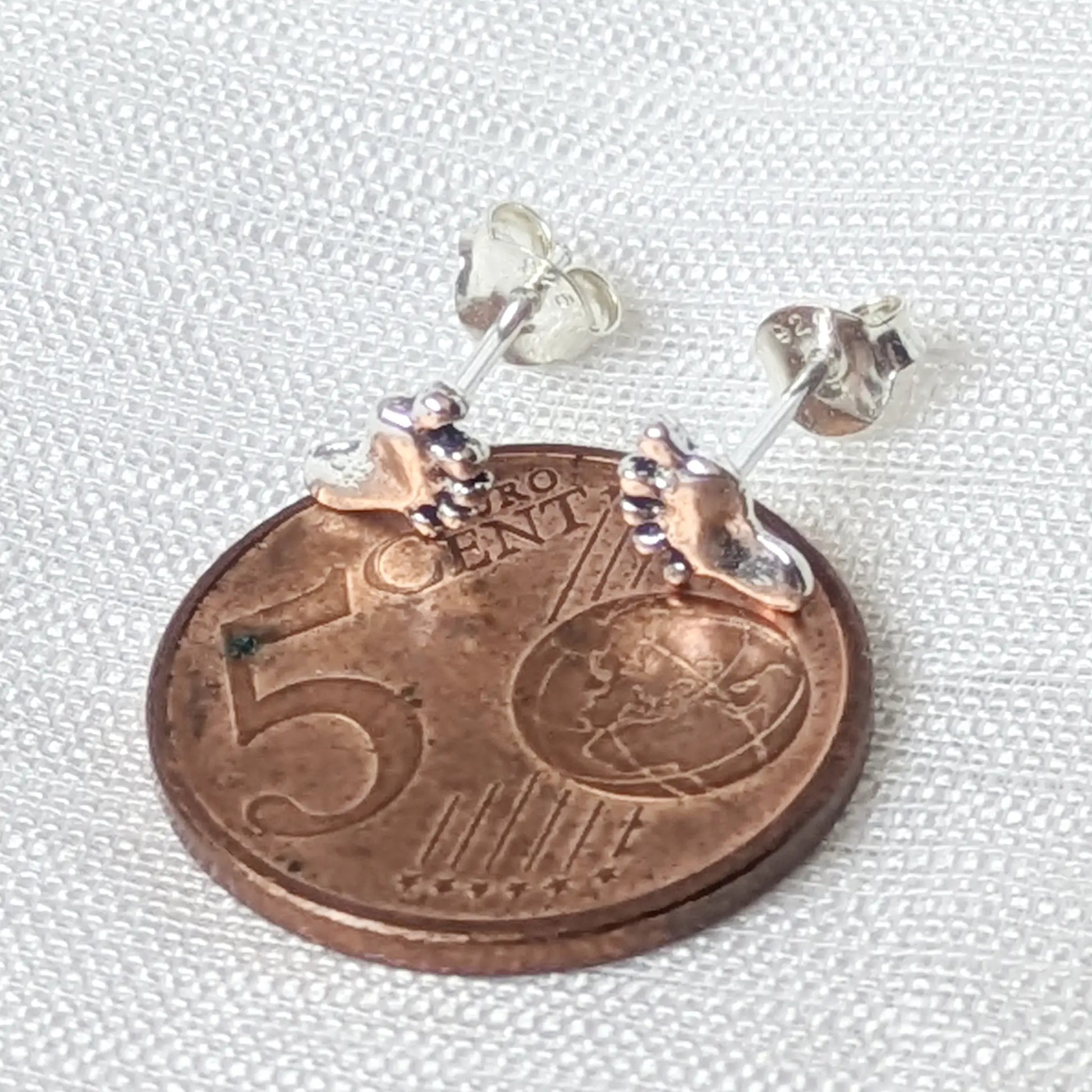Größenvergleich: Der winzige 925 Silber Fußabdruck-Ohrring auf einer 5-Cent-Münze zeigt das zierliche Design.