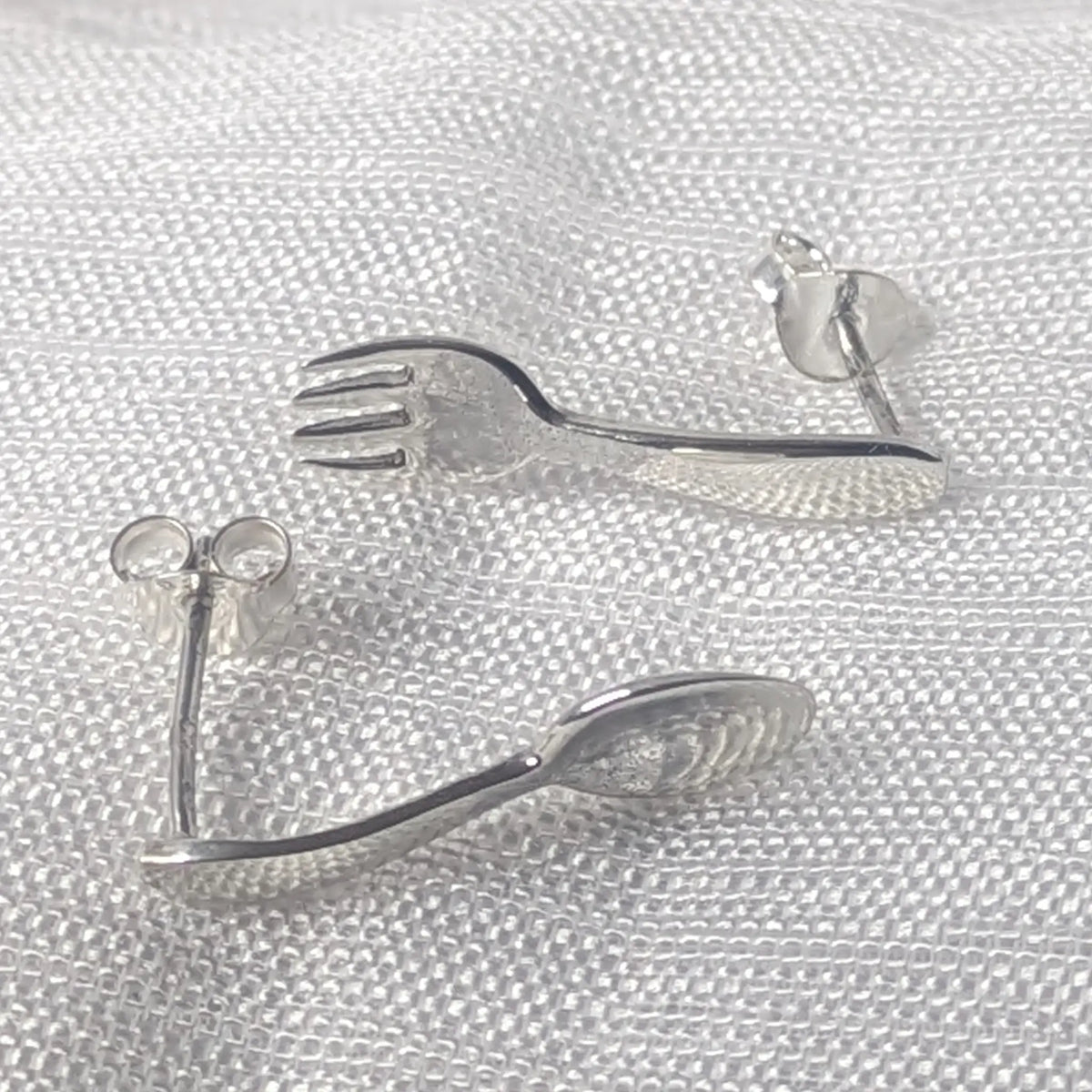 Frontalansicht der Mini-Besteck Silberohrringe mit Gabel und Löffel Motiv.
