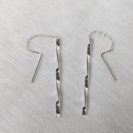 Nahaufnahme von zwei 925 Silber Durchzieher-Ohrringen mit feiner Kette und gedrehten, glänzenden Silberstäbchen im Wave-Design.