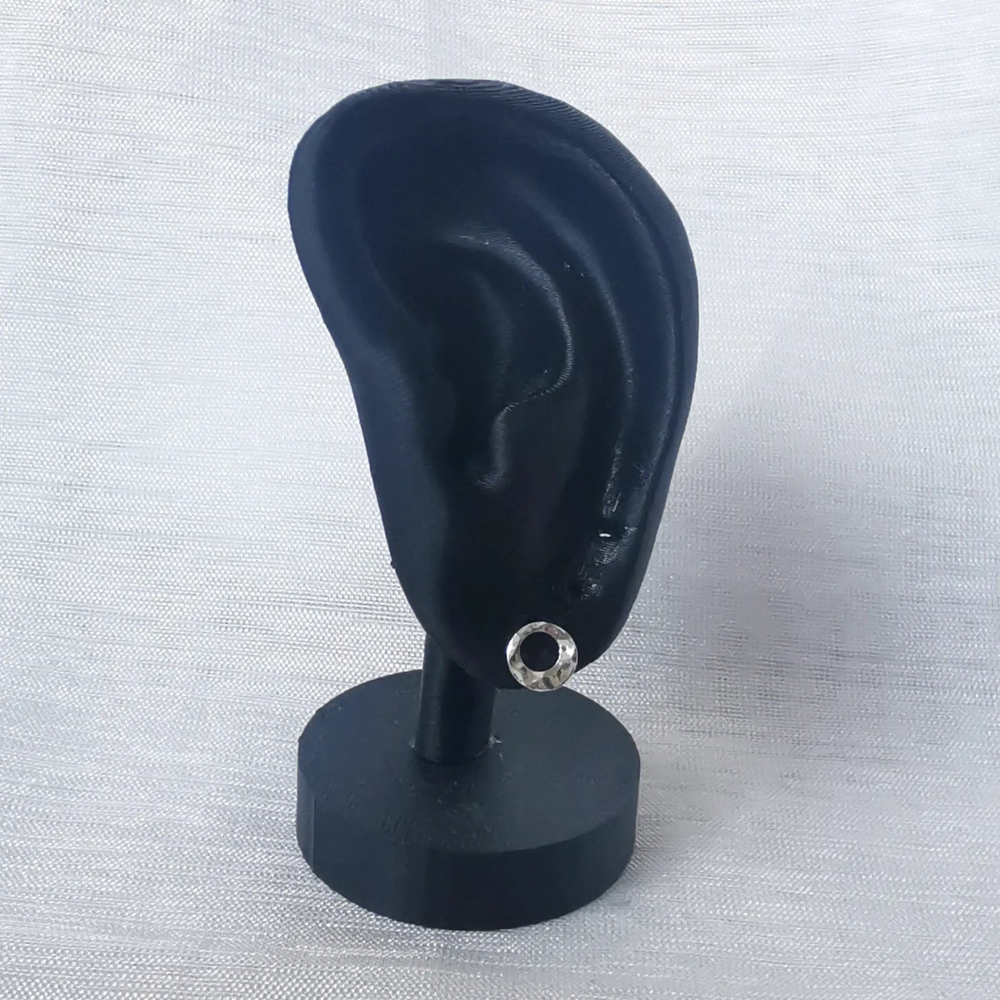 Ein offener, gehämmerter 925 Silber Kreis-Ohrstecker präsentiert an einem schwarzen Ohr-Display zur Veranschaulichung der Größe am Ohr