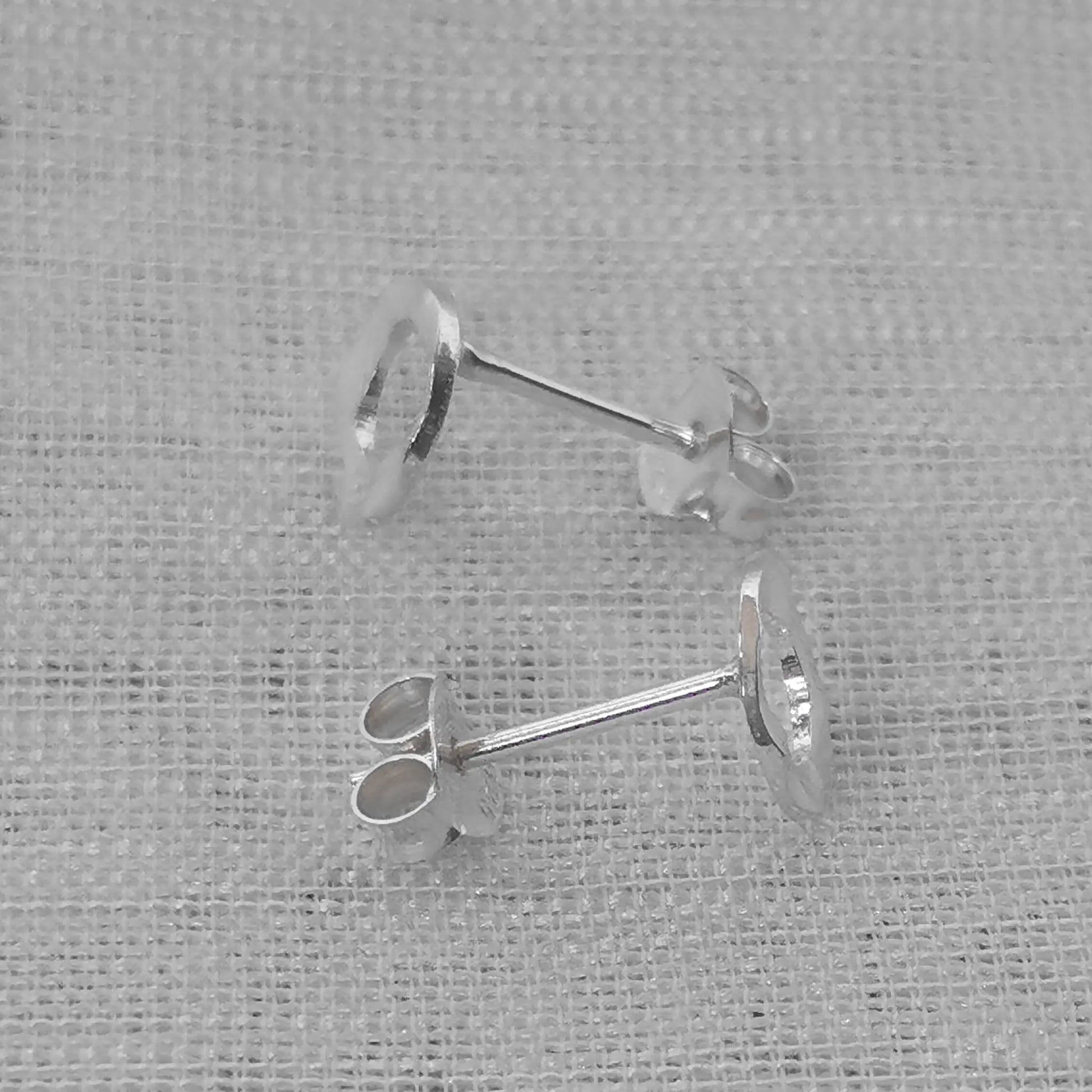 Seitenansicht der gehämmerten Silber-Ohrstecker, die das wellige Profil und den rechtwinkligen Silberstift zeigt.