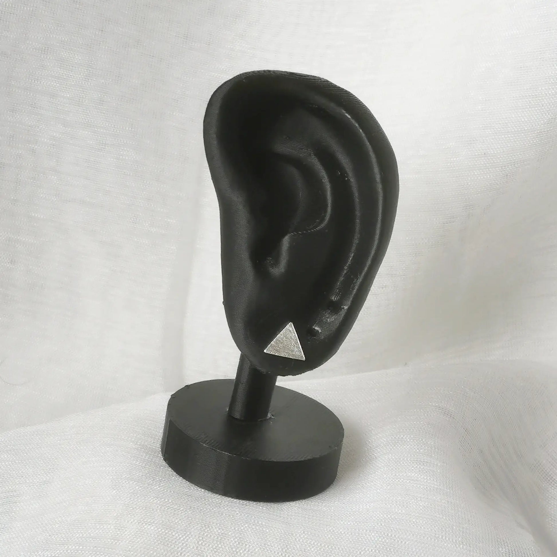 Minimalistische silberne Dreieck-Ohrstecker präsentiert auf einem schwarzen Ohr-Display zur Veranschaulichung der realen Tragegröße.