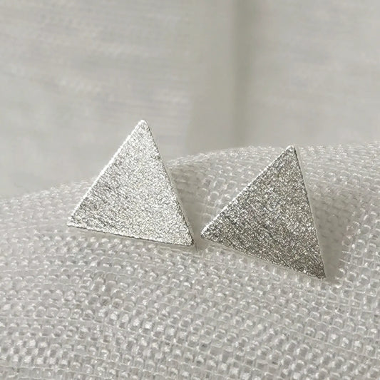 Nahaufnahme von geometrischen 925 Silber Ohrsteckern in Dreieck-Form mit detailreich gebürsteter, mattierter Oberfläche