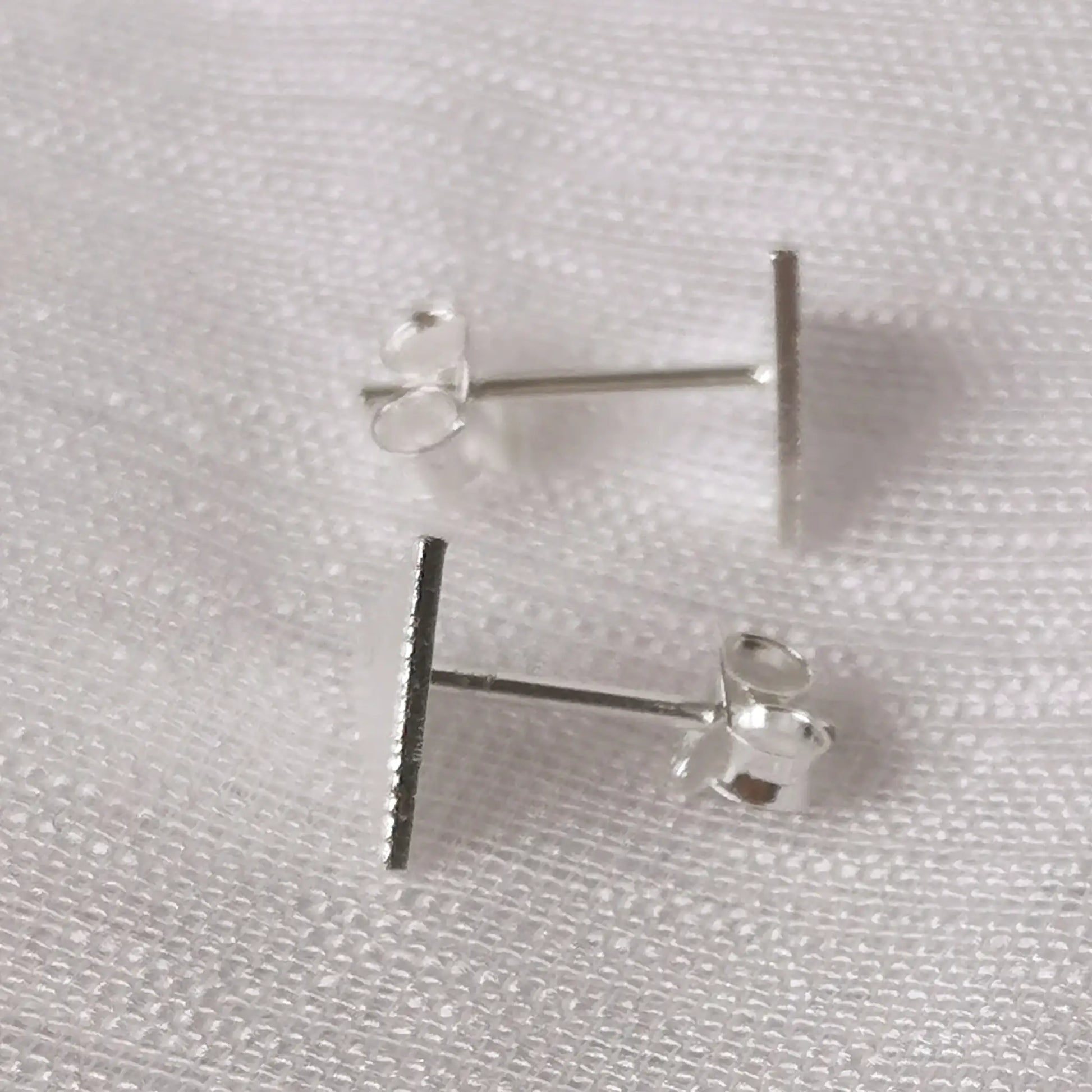 Seitliche Ansicht der silbernen Dreiecks-Ohrstecker zeigt die flache Verarbeitung und den stabilen Stecker-Stift aus 925 Silber.