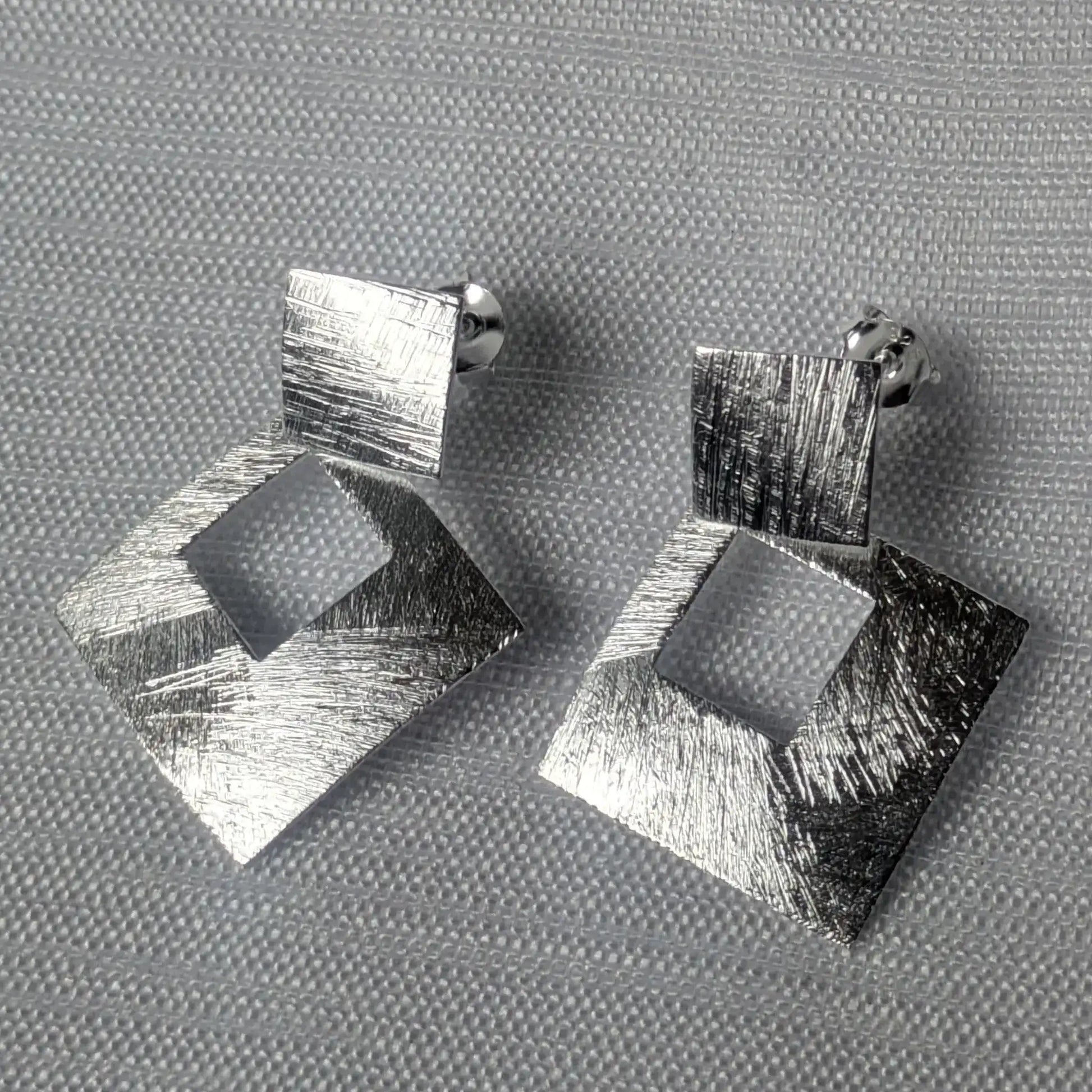 Frontalansicht der geometrischen Silberohrringe in Doppel-Quadrat-Optik.