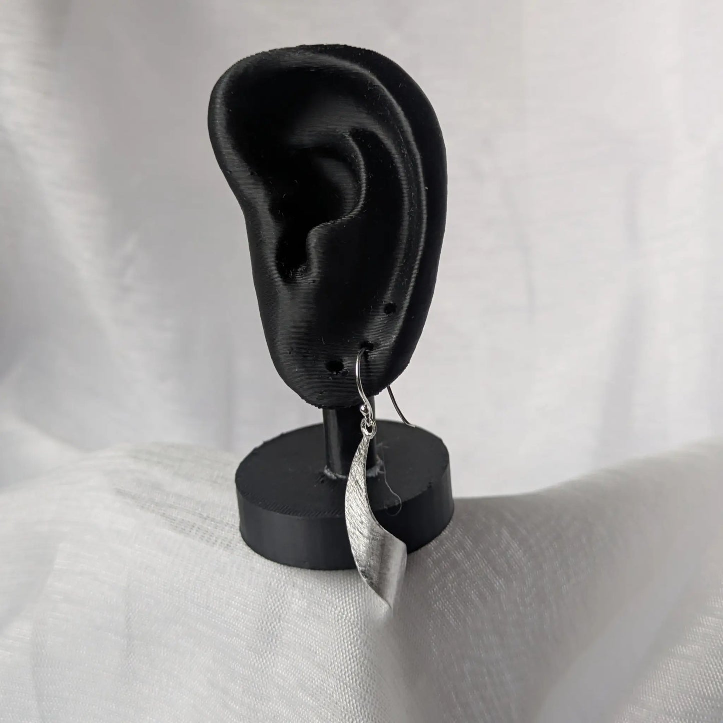 Silberne Designer-Ohrringe präsentiert auf schwarzem Schmuck-Display