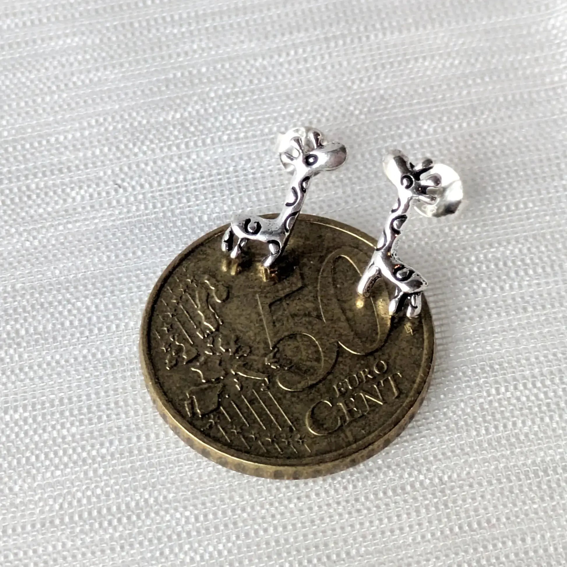 Paar Giraffe-Ohrstecker in Nahaufnahme mit 50-Cent Münze