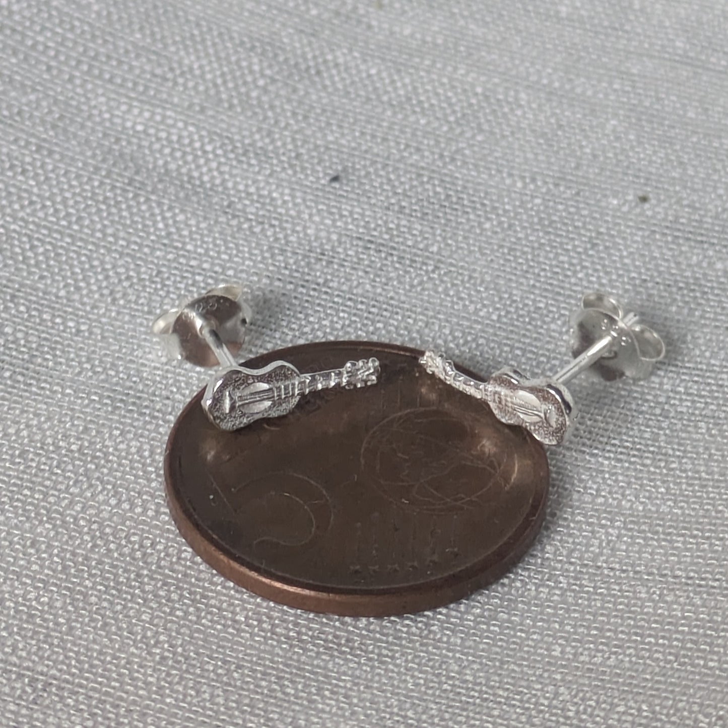 Größenvergleich der Gitarren-Ohrringe auf einer 5-Cent Münze zur Bestimmung der exakten Abmessungen des Schmuckstücks.