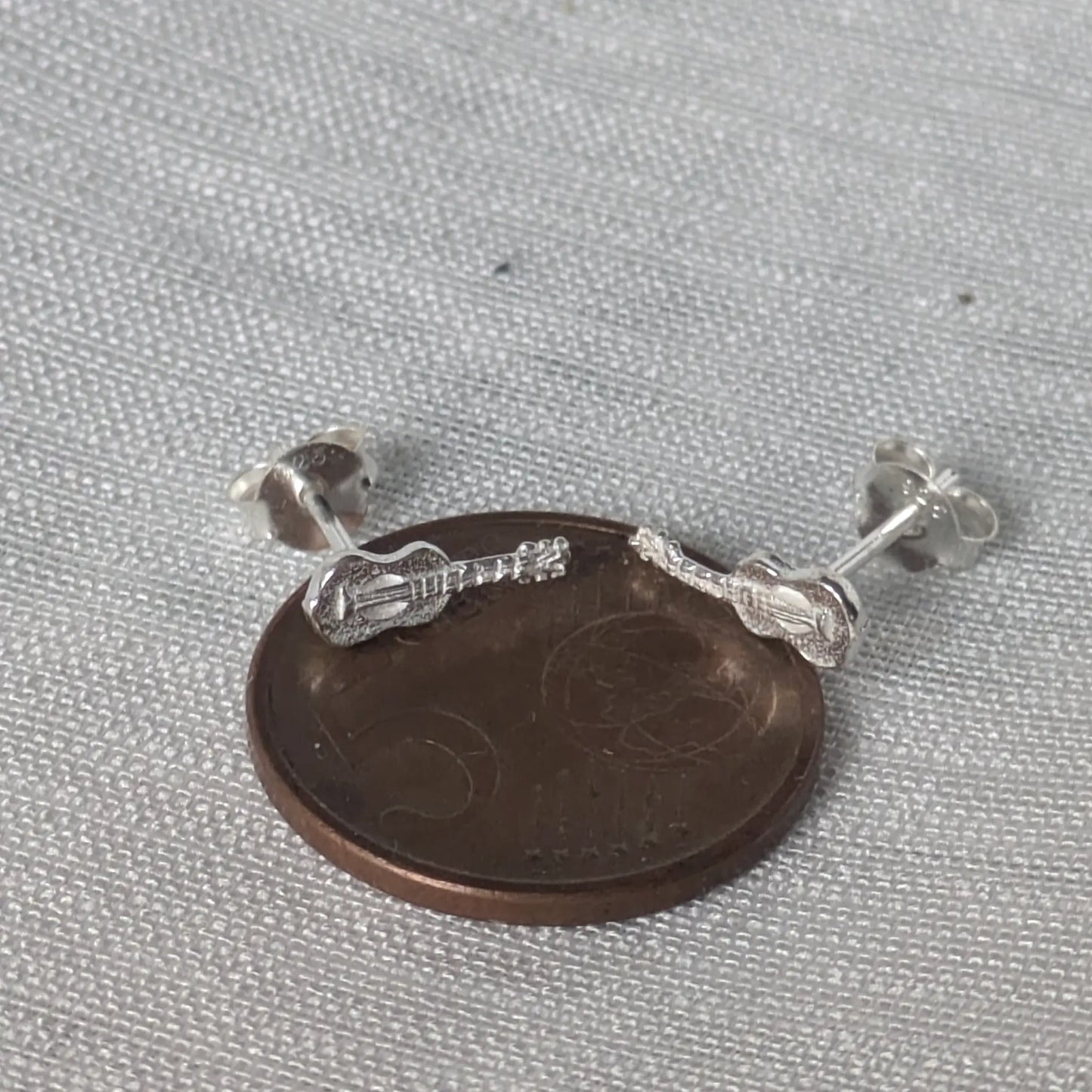 Größenvergleich der Gitarren-Ohrringe auf einer 5-Cent Münze zur Bestimmung der exakten Abmessungen des Schmuckstücks.