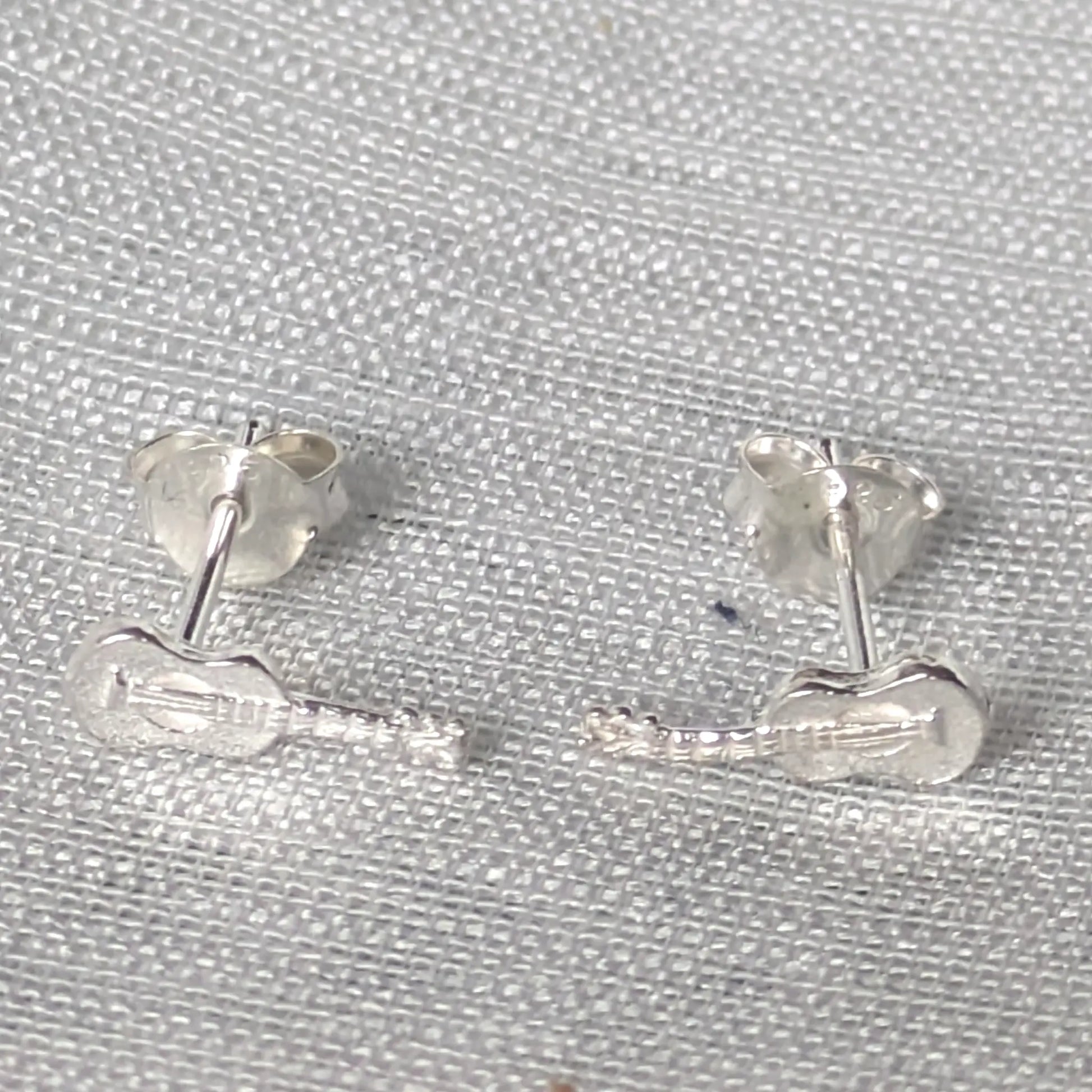 Paar silberne Gitarren Ohrstecker als dezenter Musikschmuck für Damen und Herren, präsentiert auf neutralem Hintergrund.
