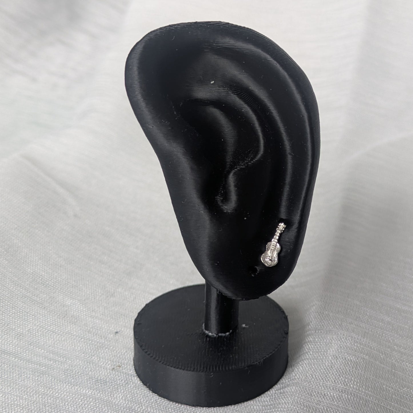 Miniatur-Gitarren Ohrstecker an einem schwarzen Ohrdisplay zur Darstellung der Proportionen und der eleganten Wirkung am Ohr.