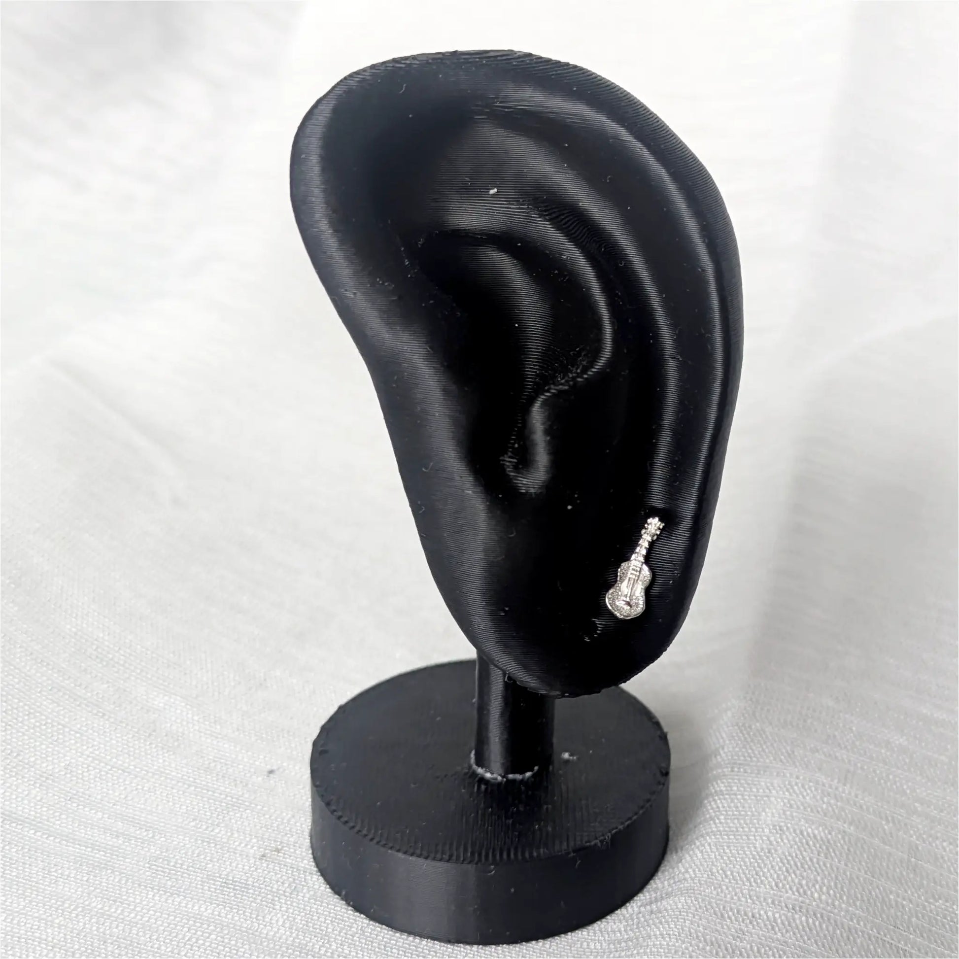 Miniatur-Gitarren Ohrstecker an einem schwarzen Ohrdisplay zur Darstellung der Proportionen und der eleganten Wirkung am Ohr.