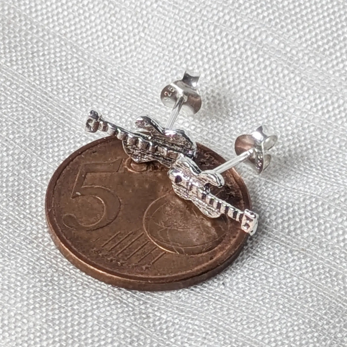 Silberner Gitarren-Ohrstecker flach auf einer 5-Cent-Münze liegend für einen realistischen und schnellen Größenvergleich.