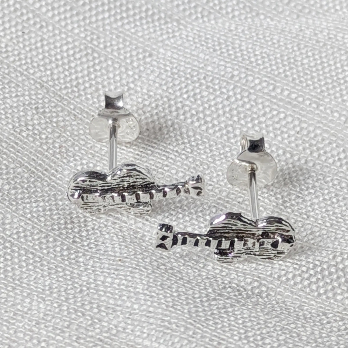 Frontalansicht der kleinen Gitarren-Ohrringe aus Silber, die die präzise Ausarbeitung von Gitarrenhals und Kopfplatte zeigt.