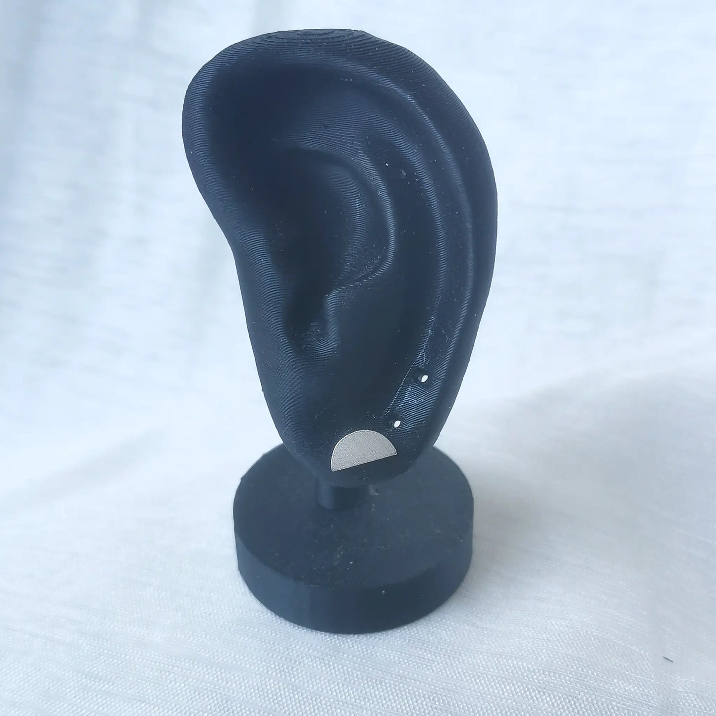 Ein mattierter 925 Silber Halbkreis-Ohrstecker präsentiert an einem schwarzen Ohr-Modell zur Veranschaulichung der modernen Wirkung am Ohr.