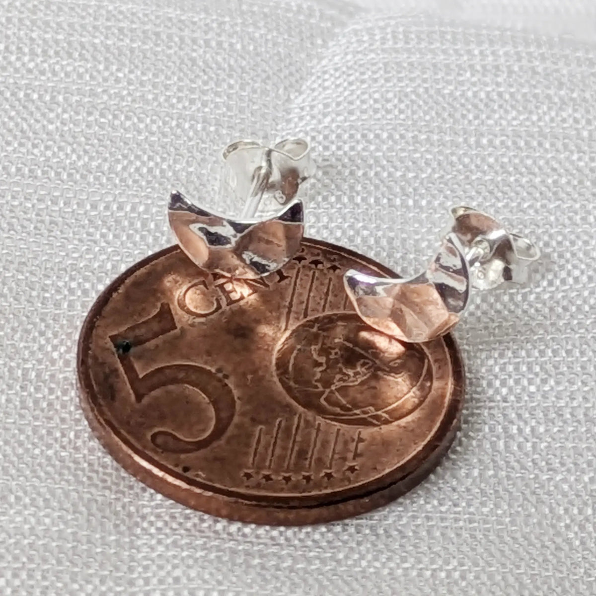 Kleine Silber-Ohrstecker in Mondform liegend auf einer 5-Cent-Münze für den exakten Größenvergleich im Alltag.