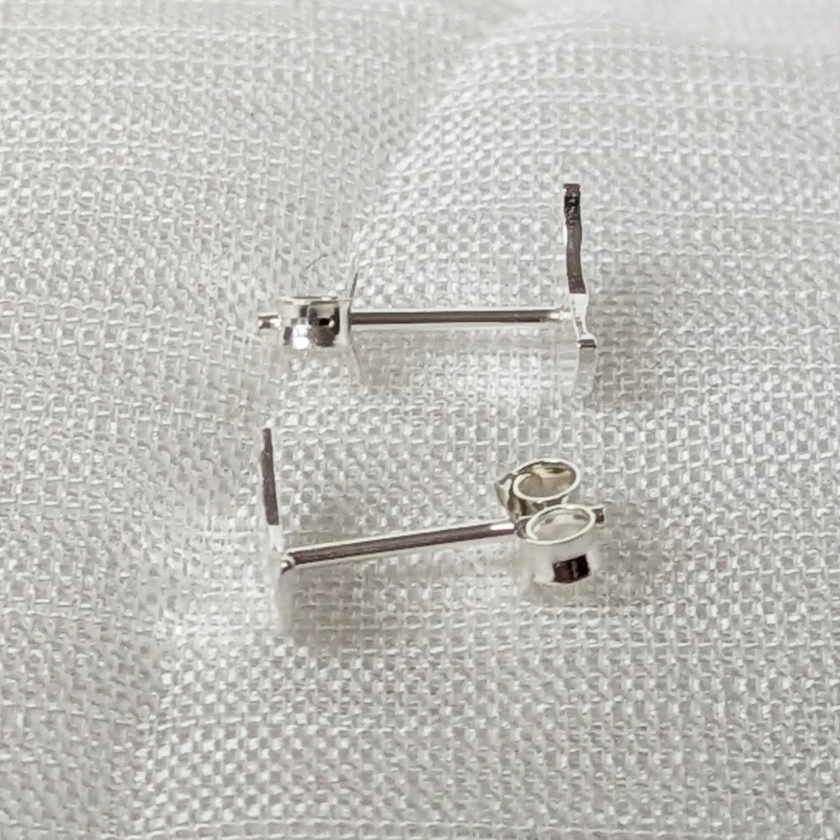 Seitenansicht der flachen Halbmond Ohrstecker aus Silber, die eng und bündig am Ohrläppchen anliegen.