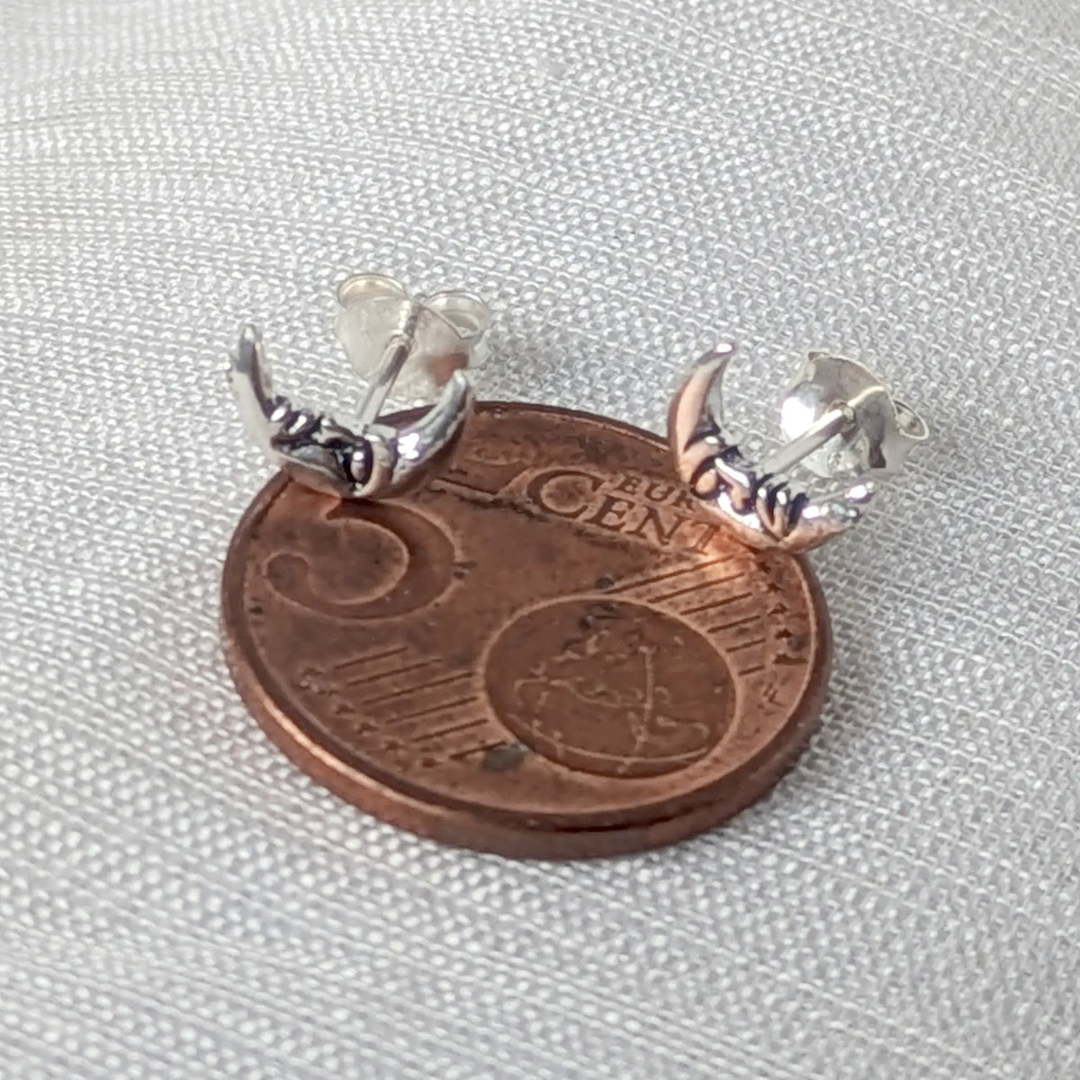 Größenvergleich: Ein 925 Silber Ohrstecker mit Mondgesicht liegt auf einer 5-Cent-Münze zur Veranschaulichung der zierlichen Abmessungen.