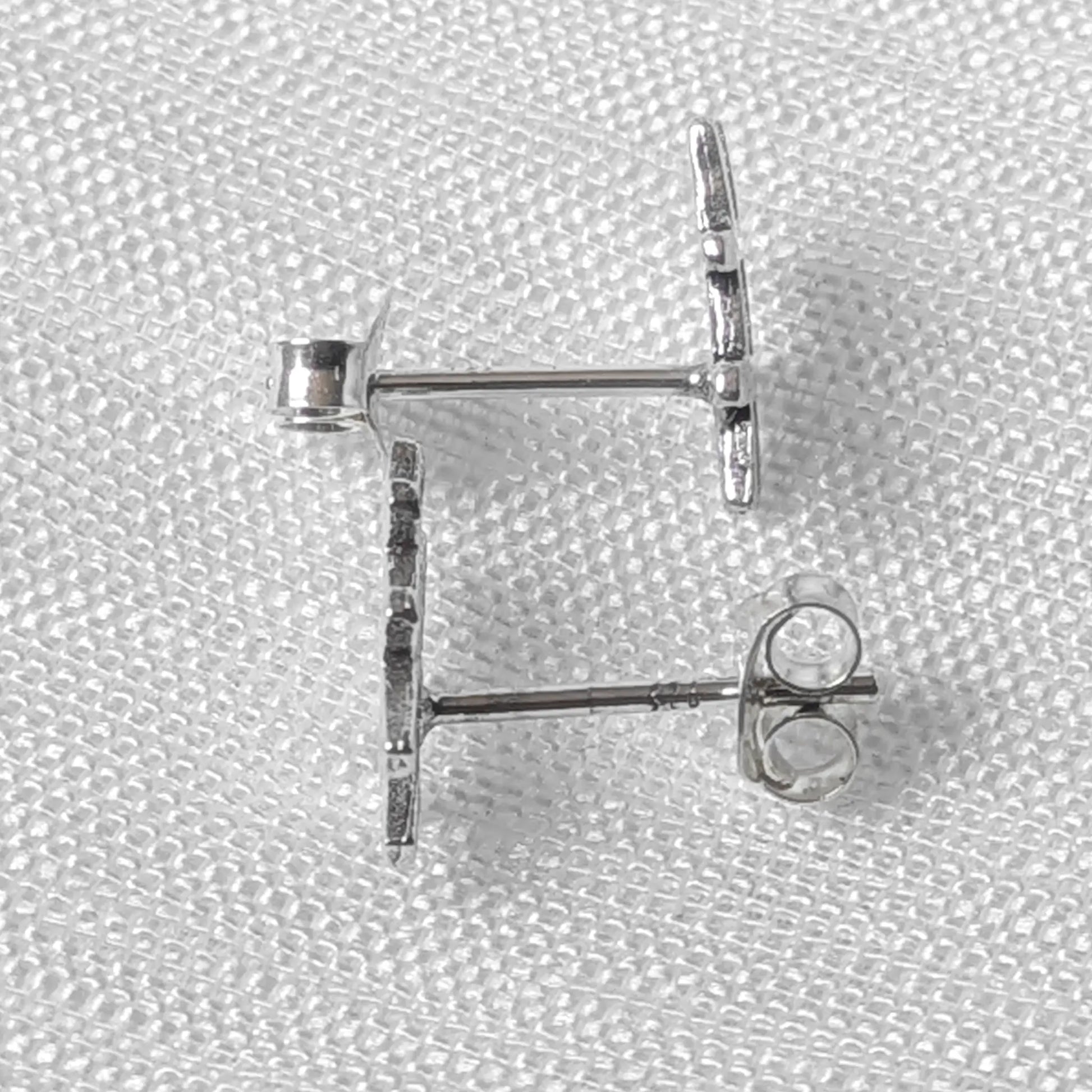 Seitliche Ansicht der silbernen Hashtag-Ohrstecker auf hellem Stoff