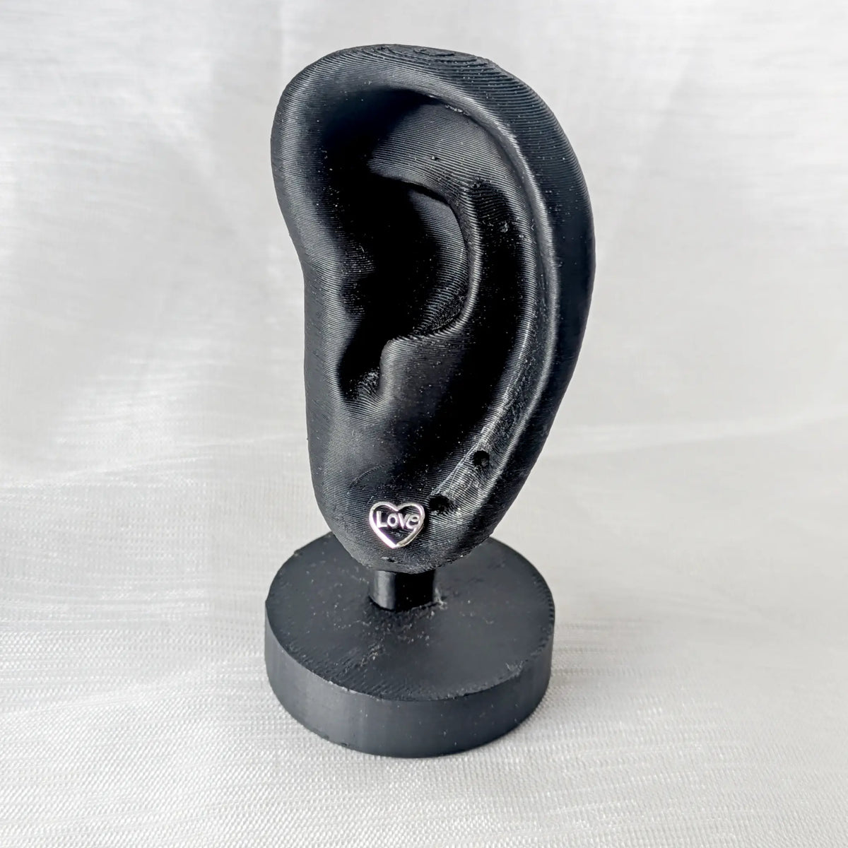 Zierlicher Silber Herz Ohrstecker Love präsentiert an einem schwarzen 3D-gedruckten Ohr-Display
