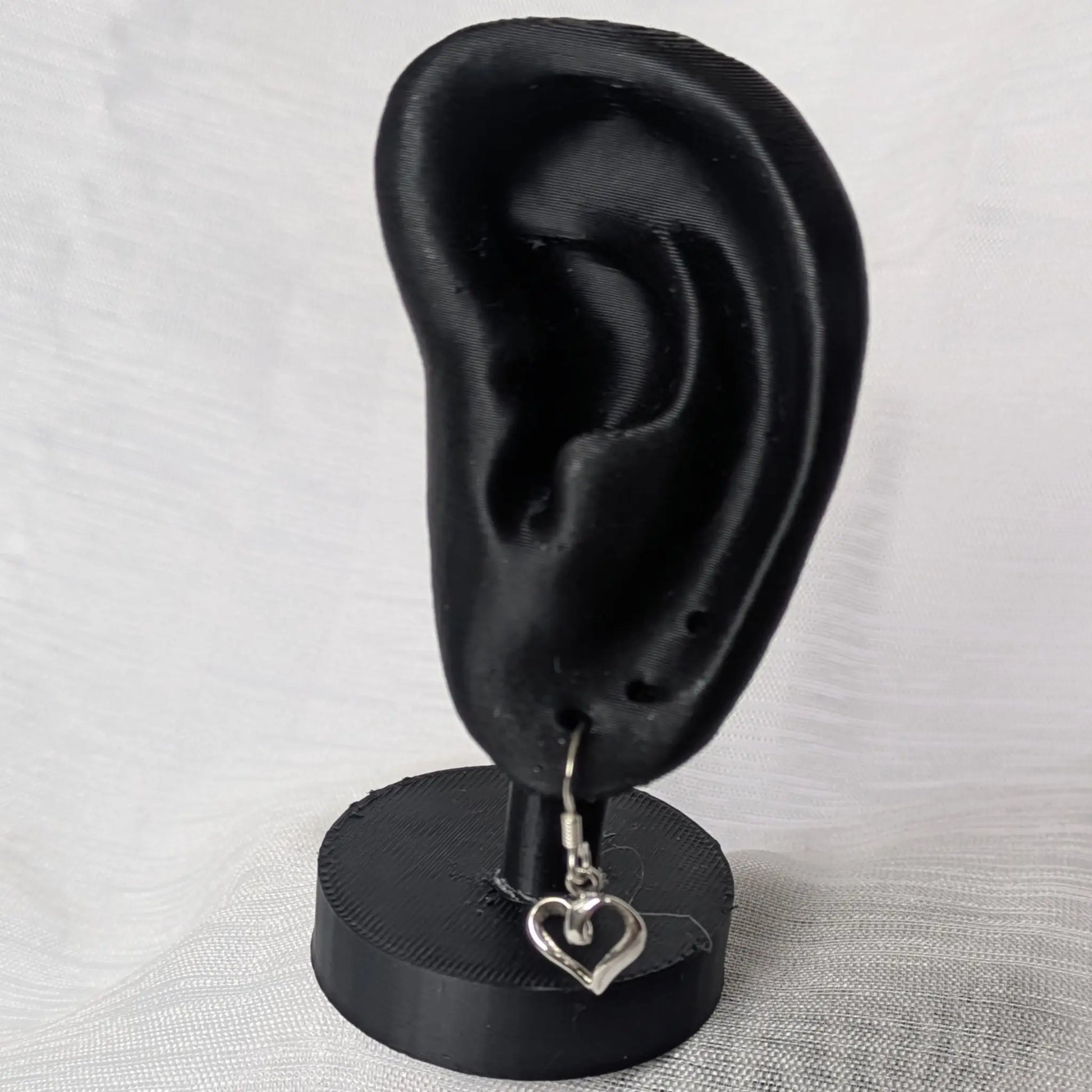 Elegante Herz-Ohrhänger an einem schwarzen Schmuck-Display präsentiert.