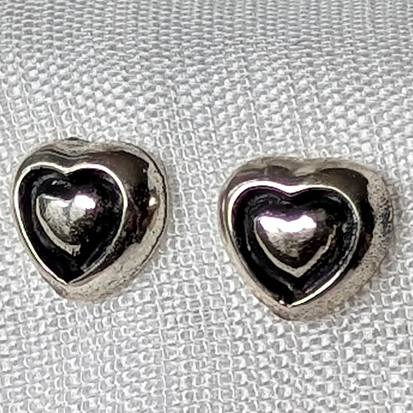 Nahaufnahme der 3D-Herz-Ohrstecker aus poliertem 925 Sterling Silber mit geschwungener Innenkontur.