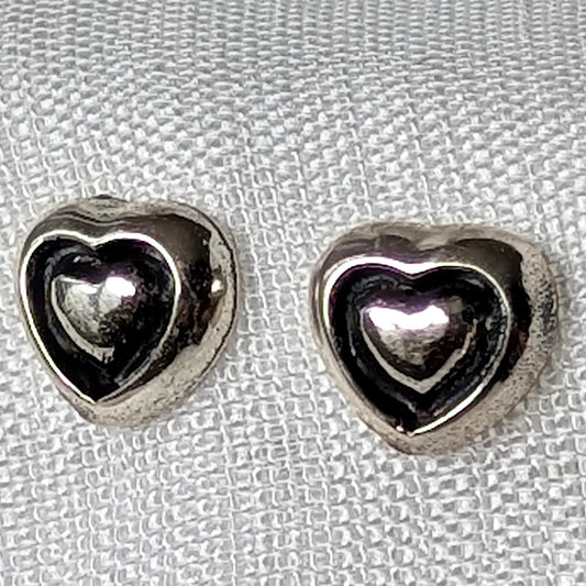 Nahaufnahme der 3D-Herz-Ohrstecker aus poliertem 925 Sterling Silber mit geschwungener Innenkontur.