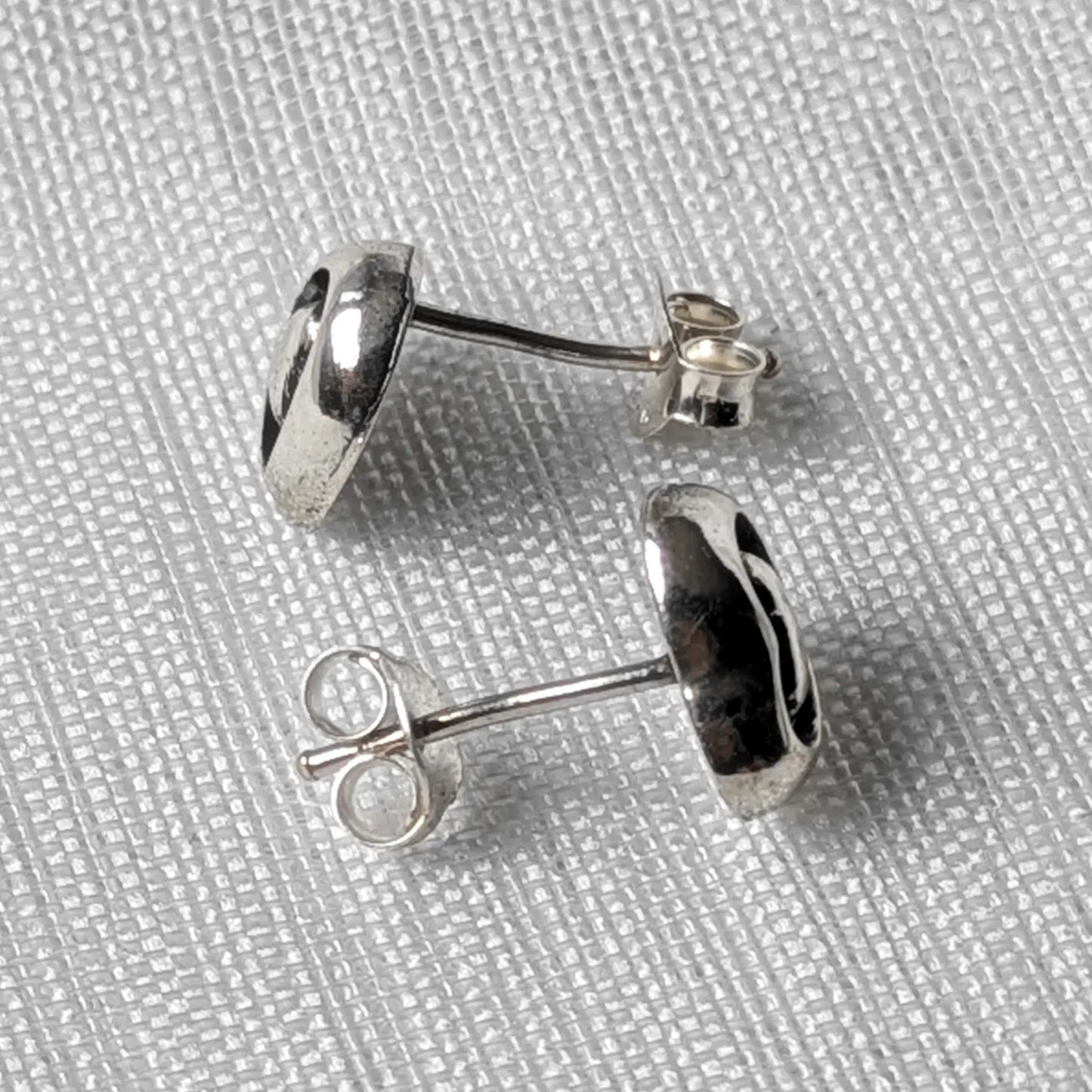 Seitenansicht der silbernen Herz-Ohrstecker zur Darstellung der plastischen Wölbung und des Steckstifts.