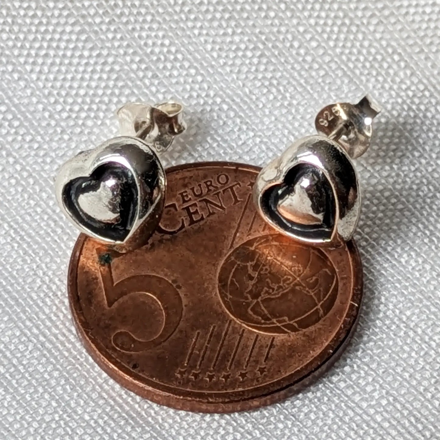 Größenvergleich der filigranen 925 Silber Herz-Ohrstecker direkt auf einer 5-Cent-Münze.