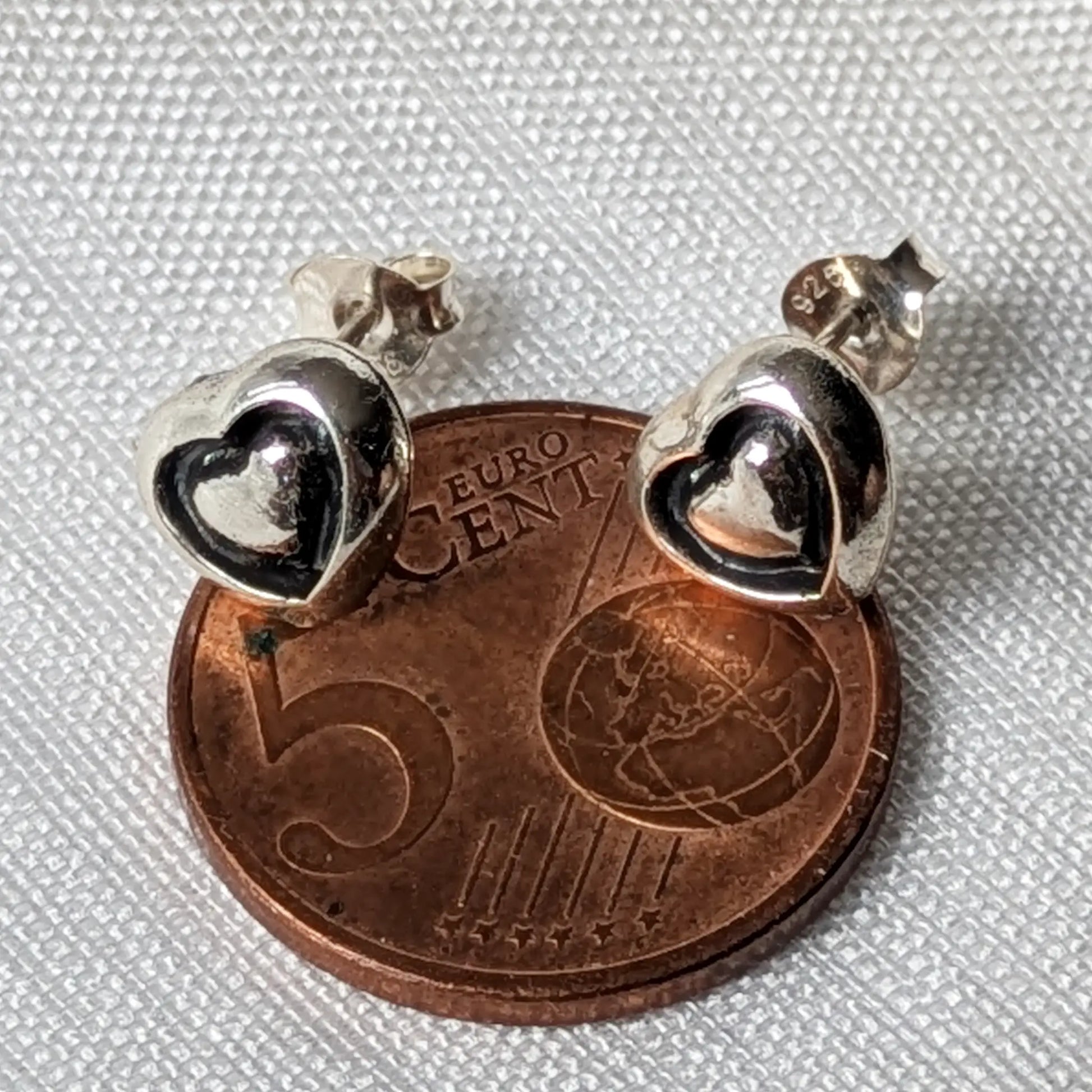 Größenvergleich der filigranen 925 Silber Herz-Ohrstecker direkt auf einer 5-Cent-Münze.