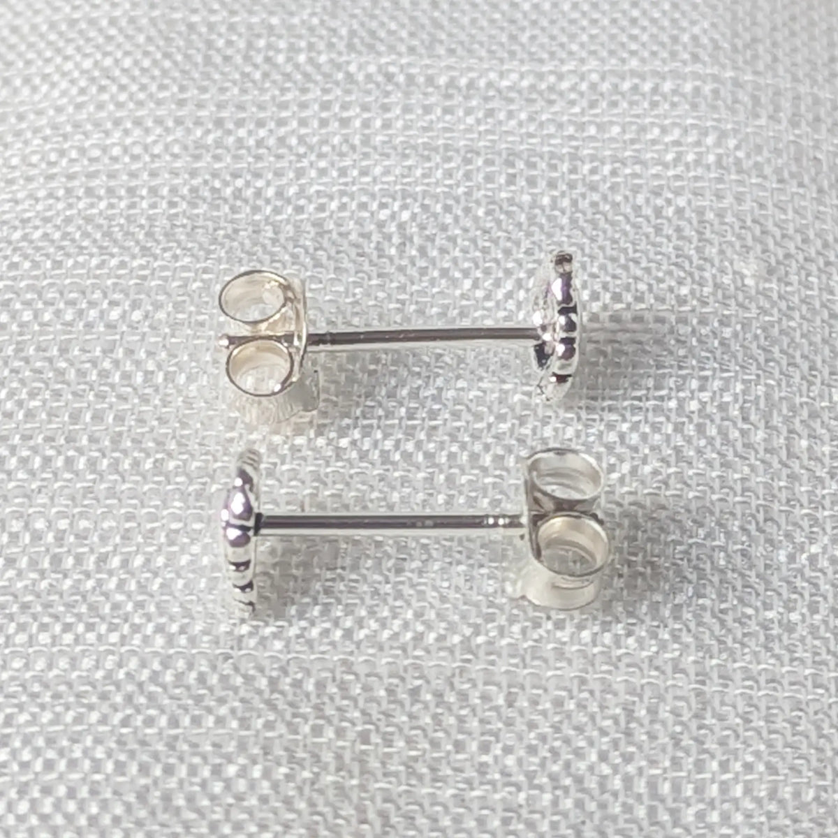 Seitenansicht der Silber-Ohrstecker, die den geraden Stift und das flach anliegende Herz-Design verdeutlicht.
