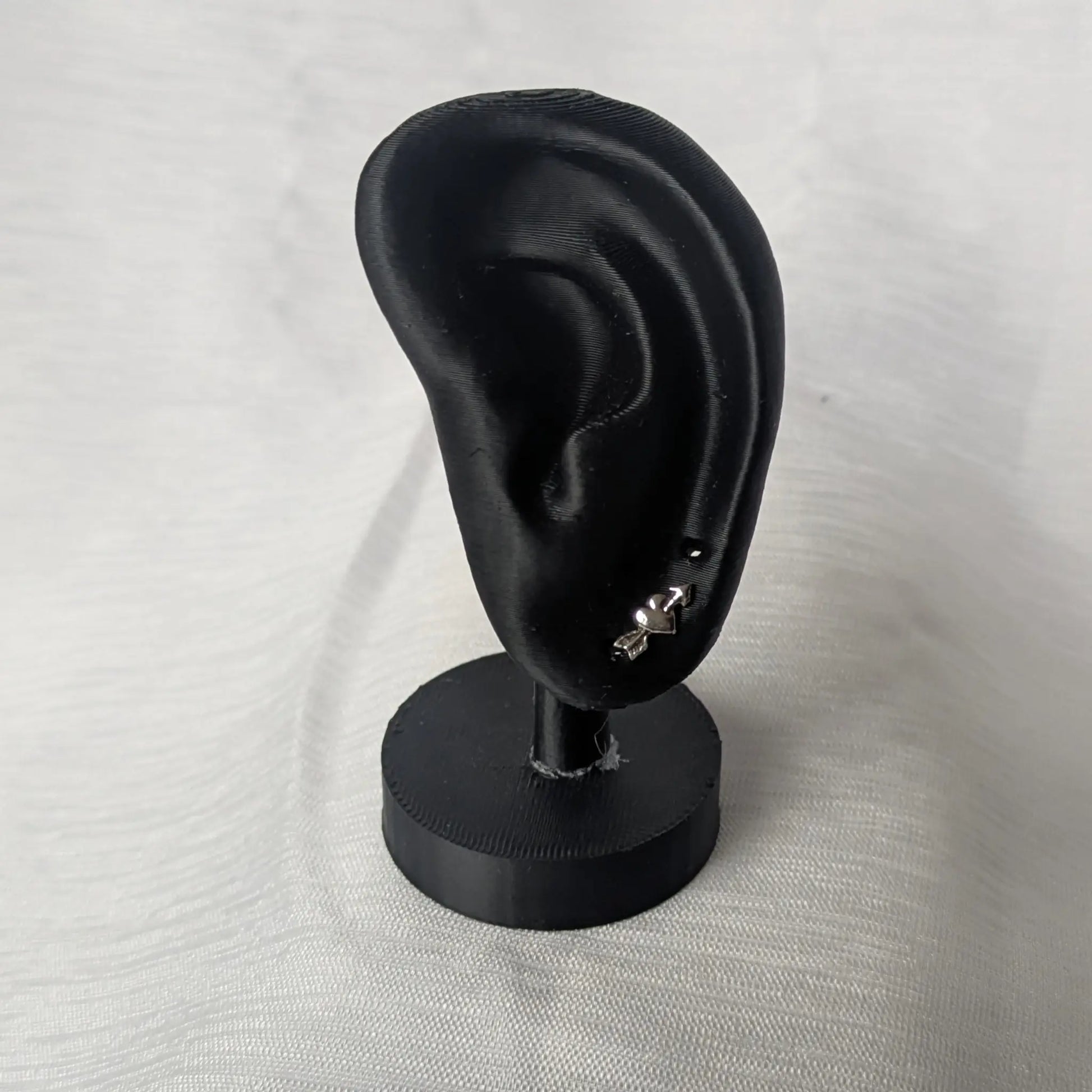 Herz-Pfeil Ohrringe präsentiert auf schwarzem Schmuck-Display.