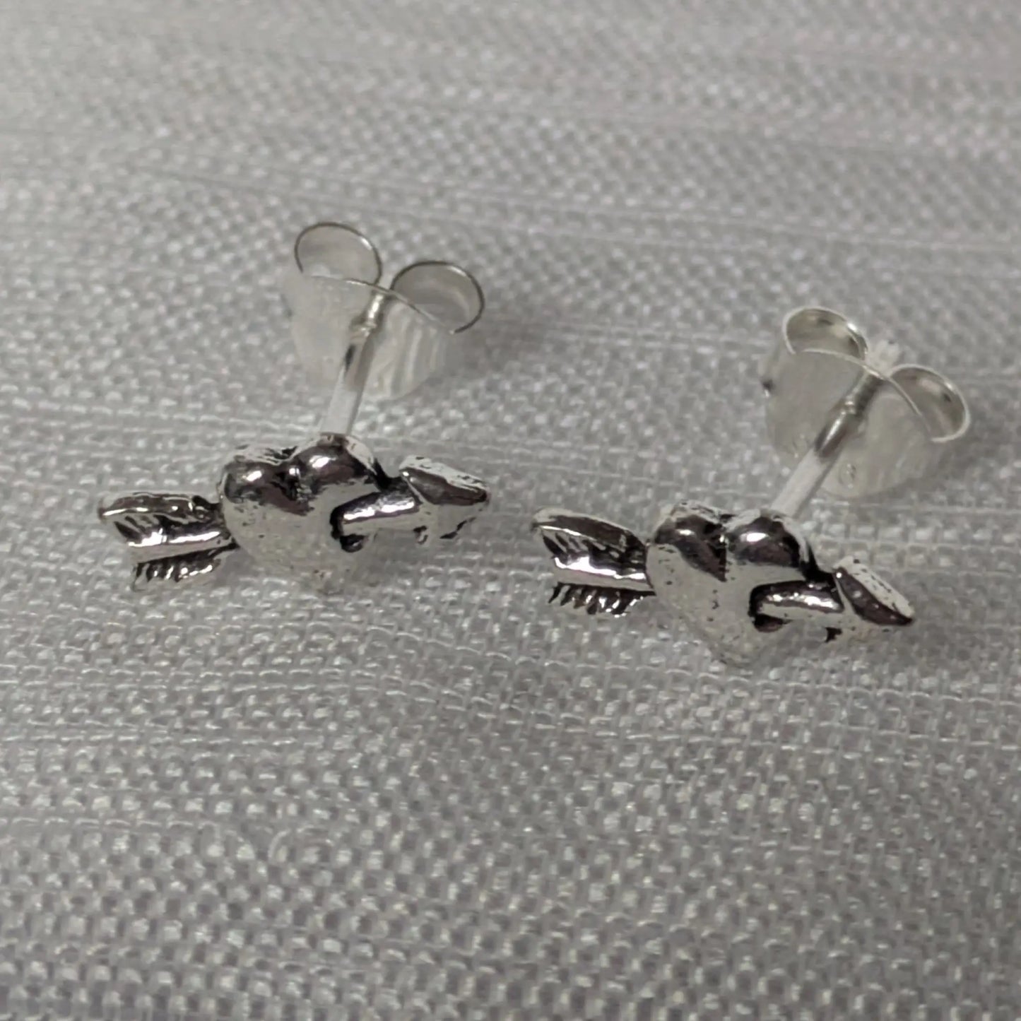 Frontalansicht der Amor Herzohrringe aus Silber mit oxidierten Details.
