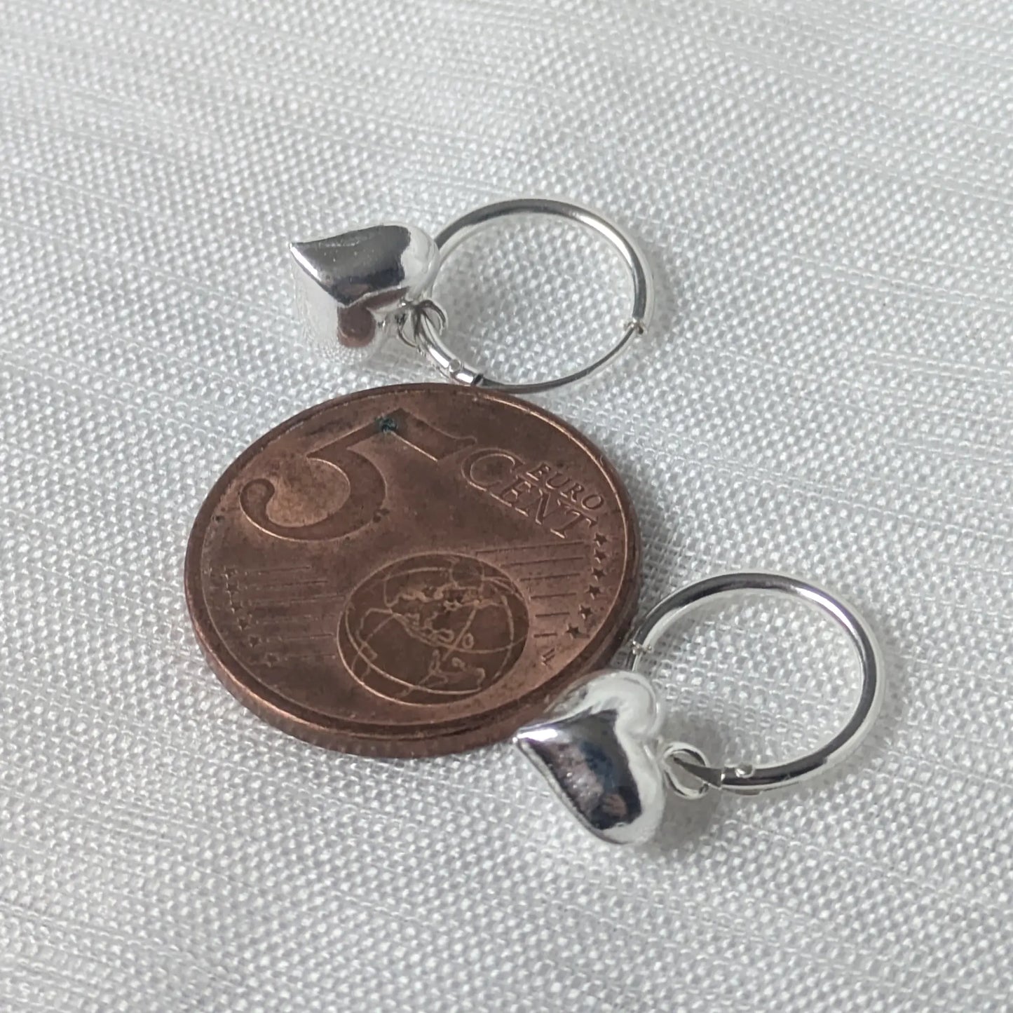 Größenvergleich der filigranen Herz-Ohrringe aus Silber platziert auf einer 5-Cent-Münze zur Veranschaulichung der Maße.