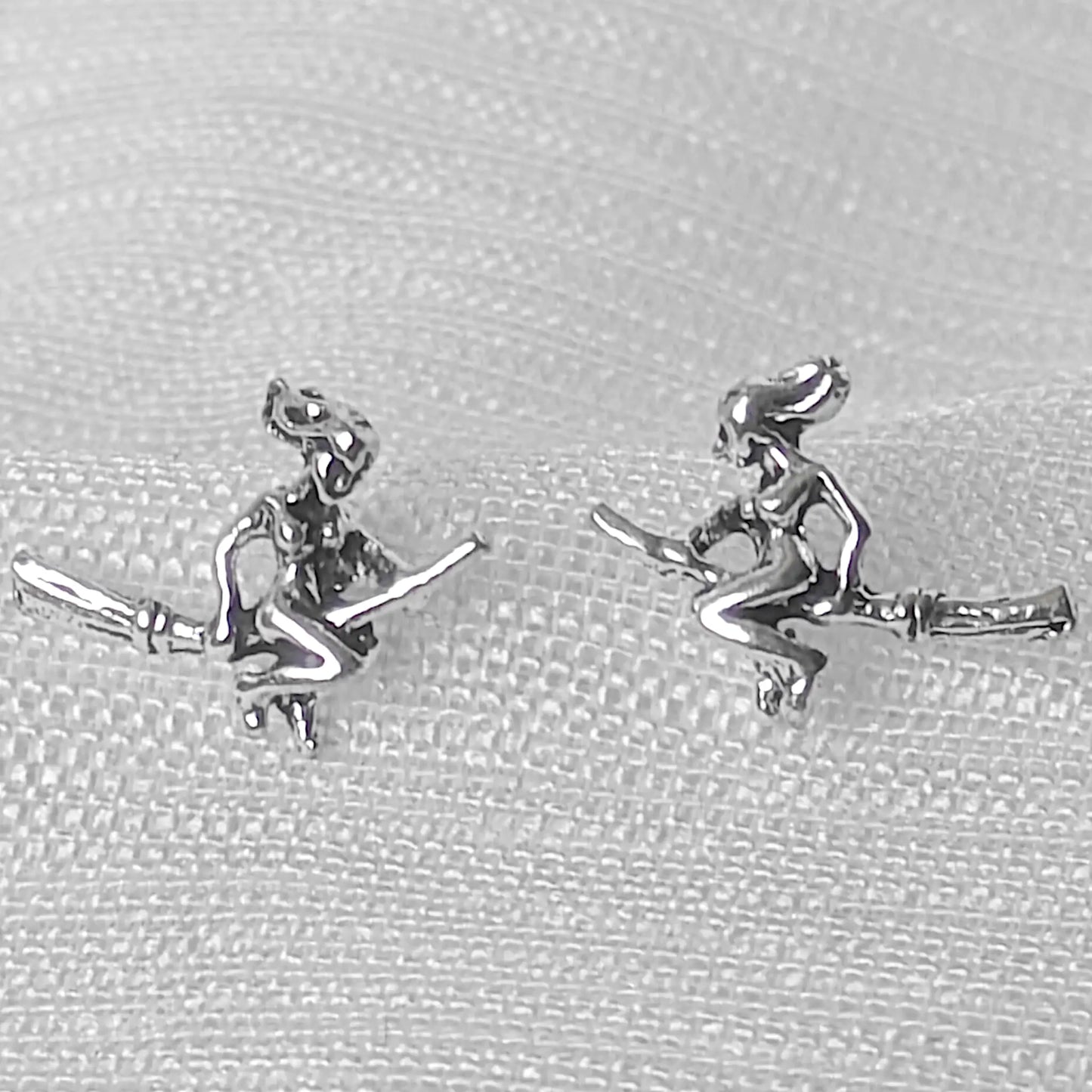 Nahaufnahme von zwei filigranen Hexen-Ohrsteckern aus glänzendem 925 Sterling Silber mit sichtbaren Details.