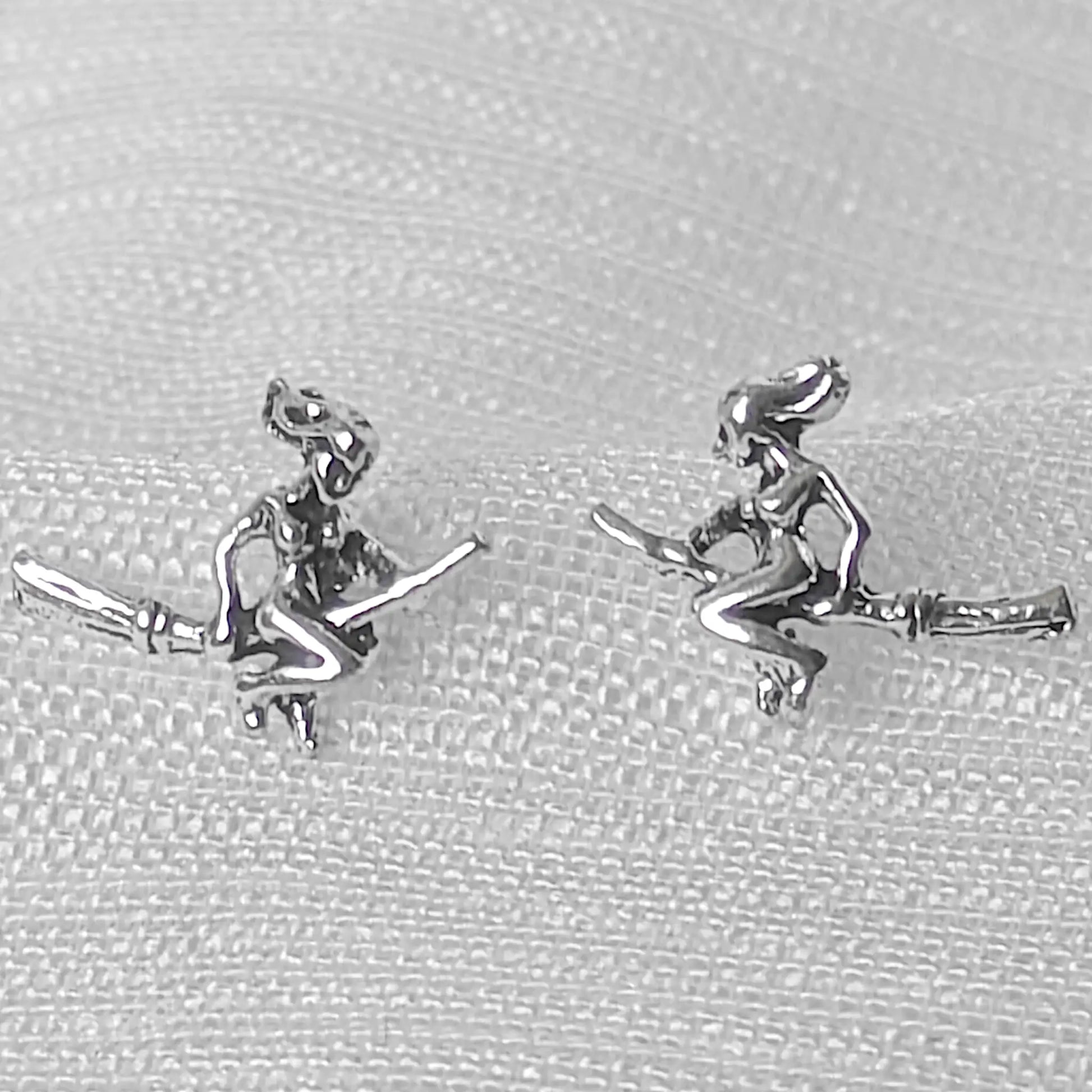 Nahaufnahme von zwei filigranen Hexen-Ohrsteckern aus glänzendem 925 Sterling Silber mit sichtbaren Details.