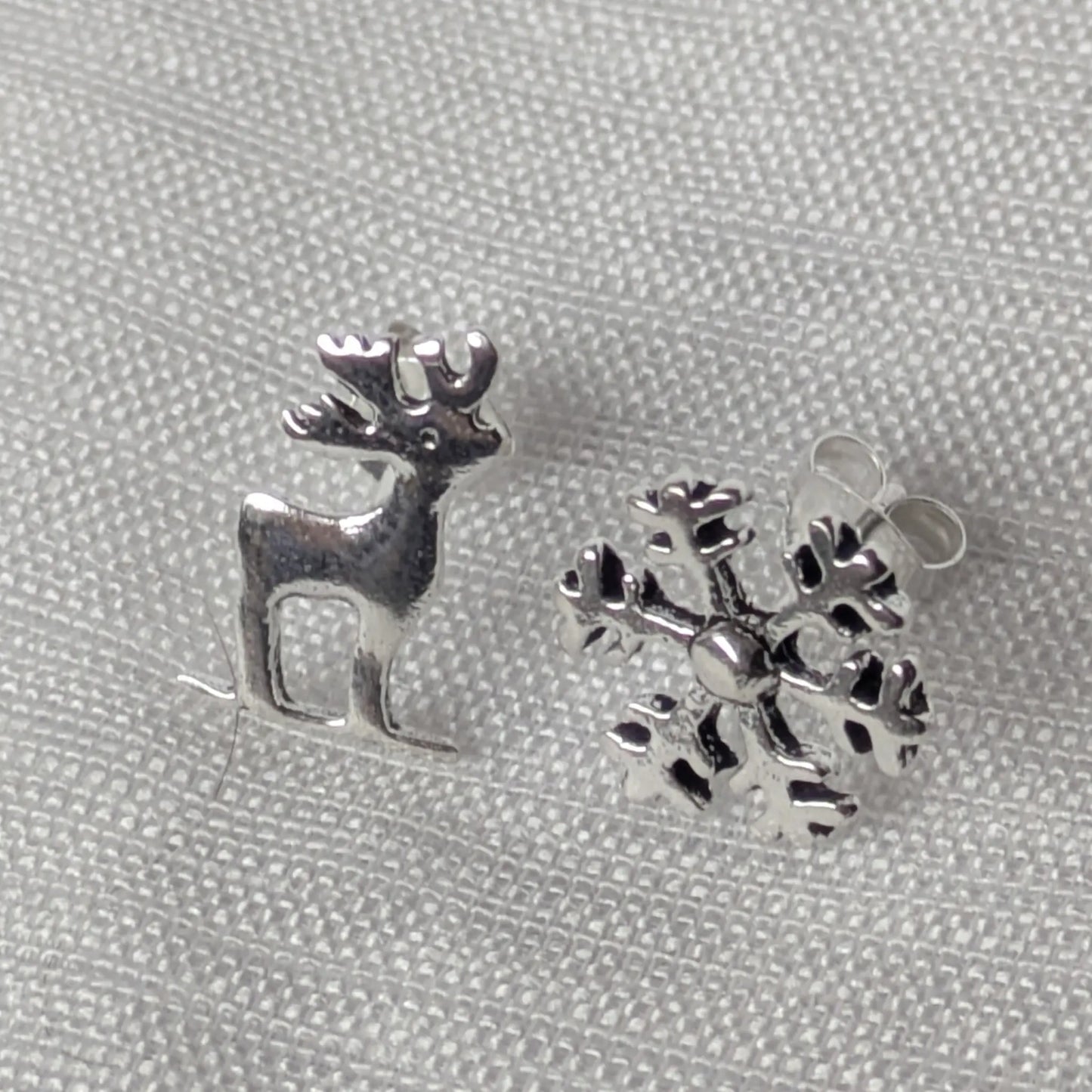 Frontale Ansicht des vierteiligen Sets: Hirsch und Schneeflocke Ohrringe aus echtem Silber.