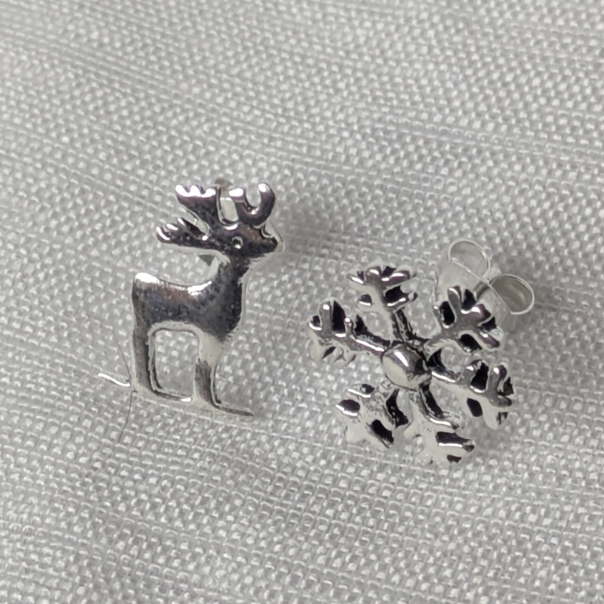 Frontale Ansicht des vierteiligen Sets: Hirsch und Schneeflocke Ohrringe aus echtem Silber.