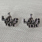 Lade das Bild in den Galerie-Viewer, Frontalansicht der silbernen 'I Love You' Ohrstecker mit antikem Finish auf weißem strukturiertem Stoff.
