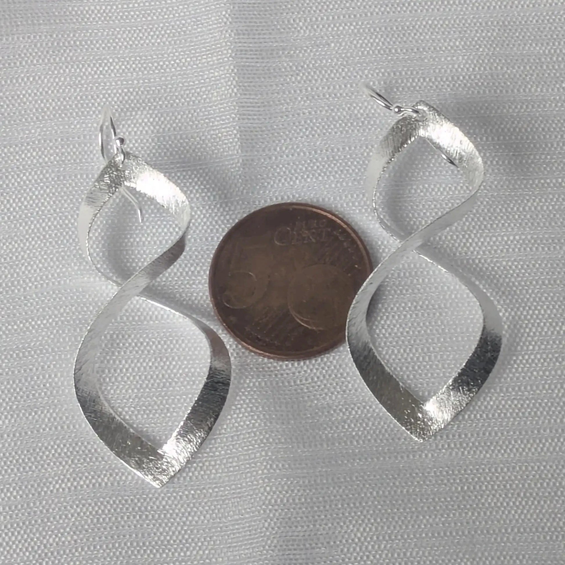 Größenvergleich 925 Silber Infinity Ohrhänger neben 5-Cent Münze.