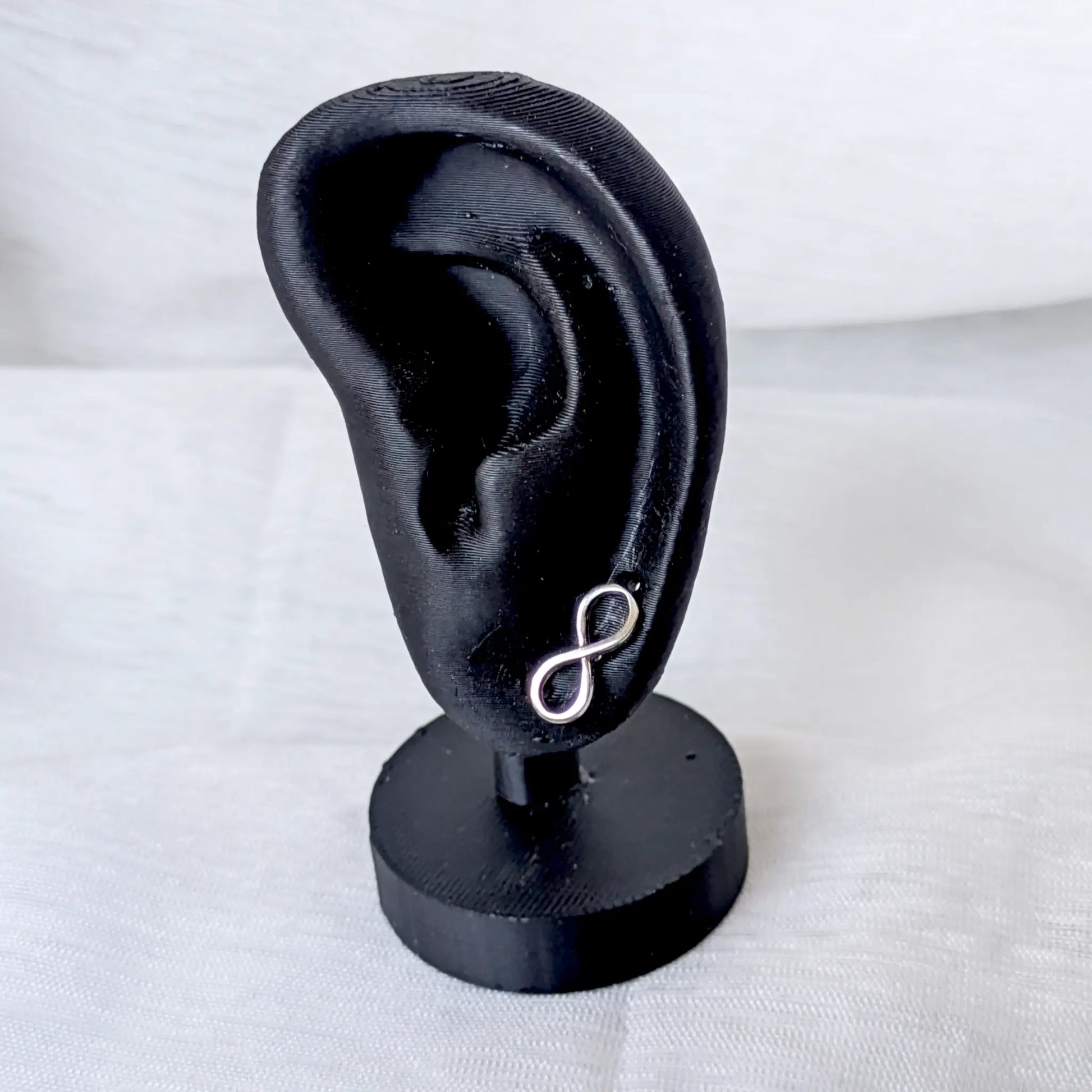 Filigraner Unendlichkeitszeichen-Ohrstecker aus 925 Silber getragen an einem schwarzen Ohr-Display.
