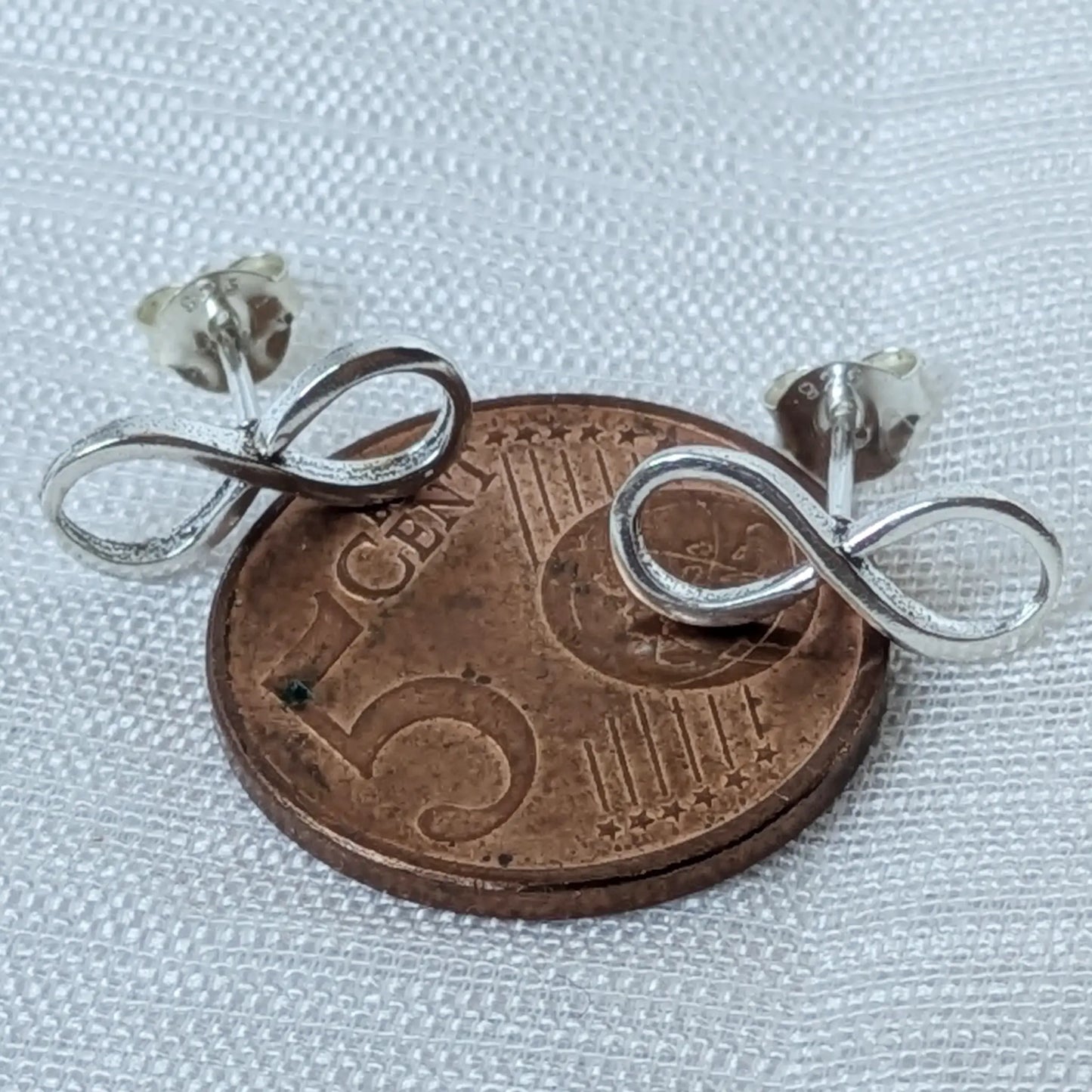 Größenvergleich der filigranen 925 Silber Infinity Ohrstecker auf einer 5-Cent-Münze.