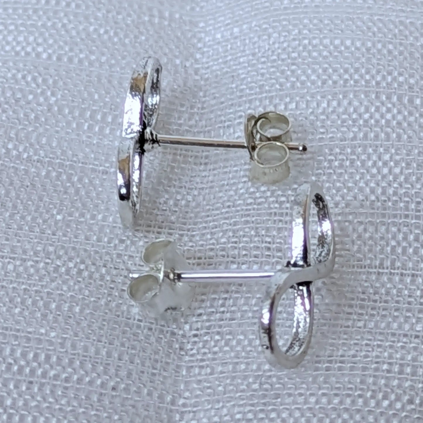 Seitenansicht der silbernen Infinity Ohrstecker mit Steckerstift und polierter Oberfläche.