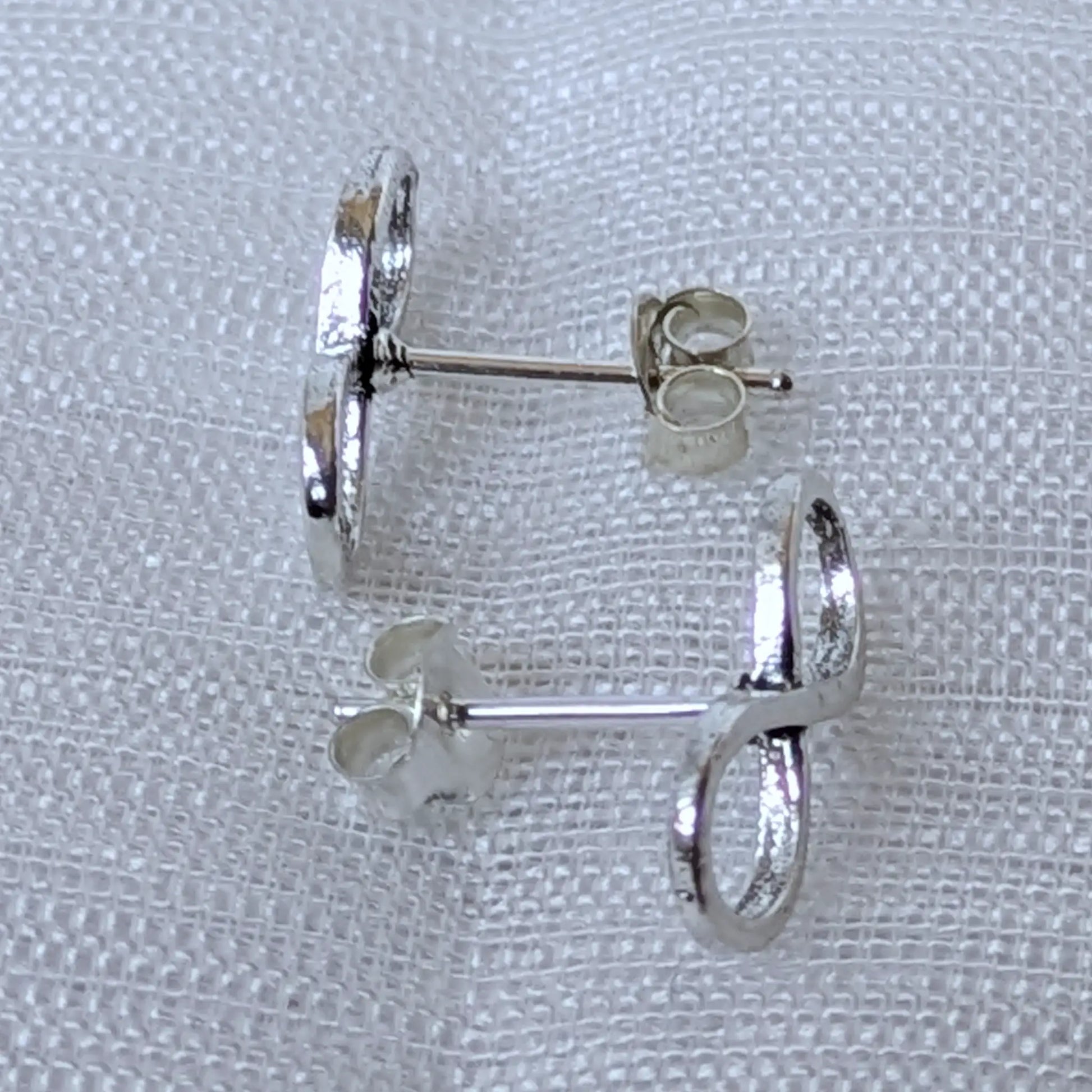 Seitenansicht der silbernen Infinity Ohrstecker mit Steckerstift und polierter Oberfläche.
