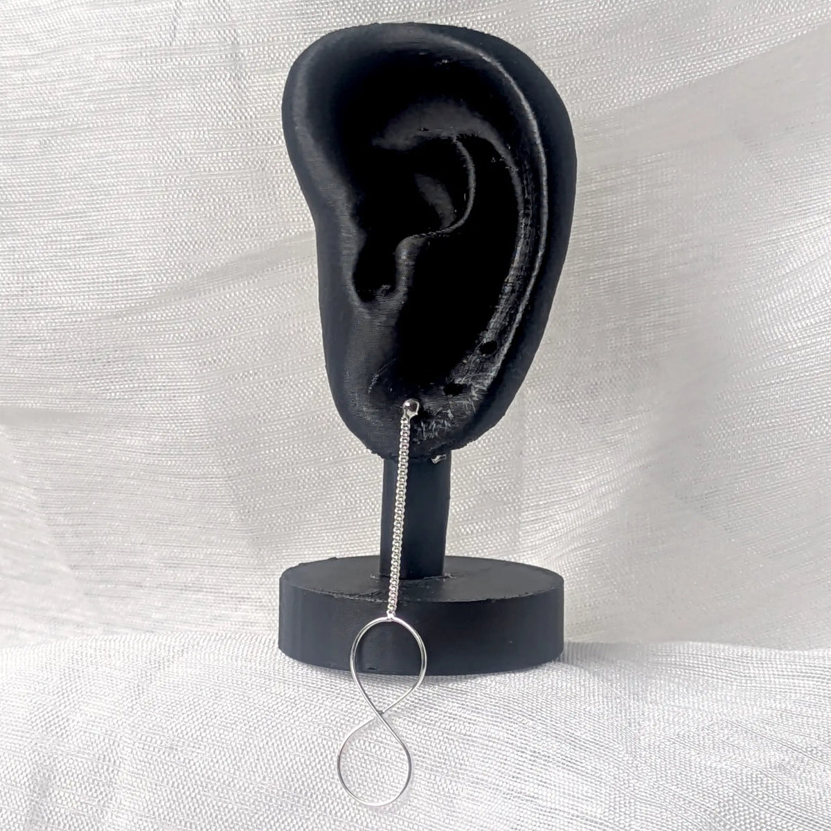 Langer 925 Silber Infinity-Ohrstecker an schwarzem 3D-Ohr-Display zur Veranschaulichung der Tragelänge.