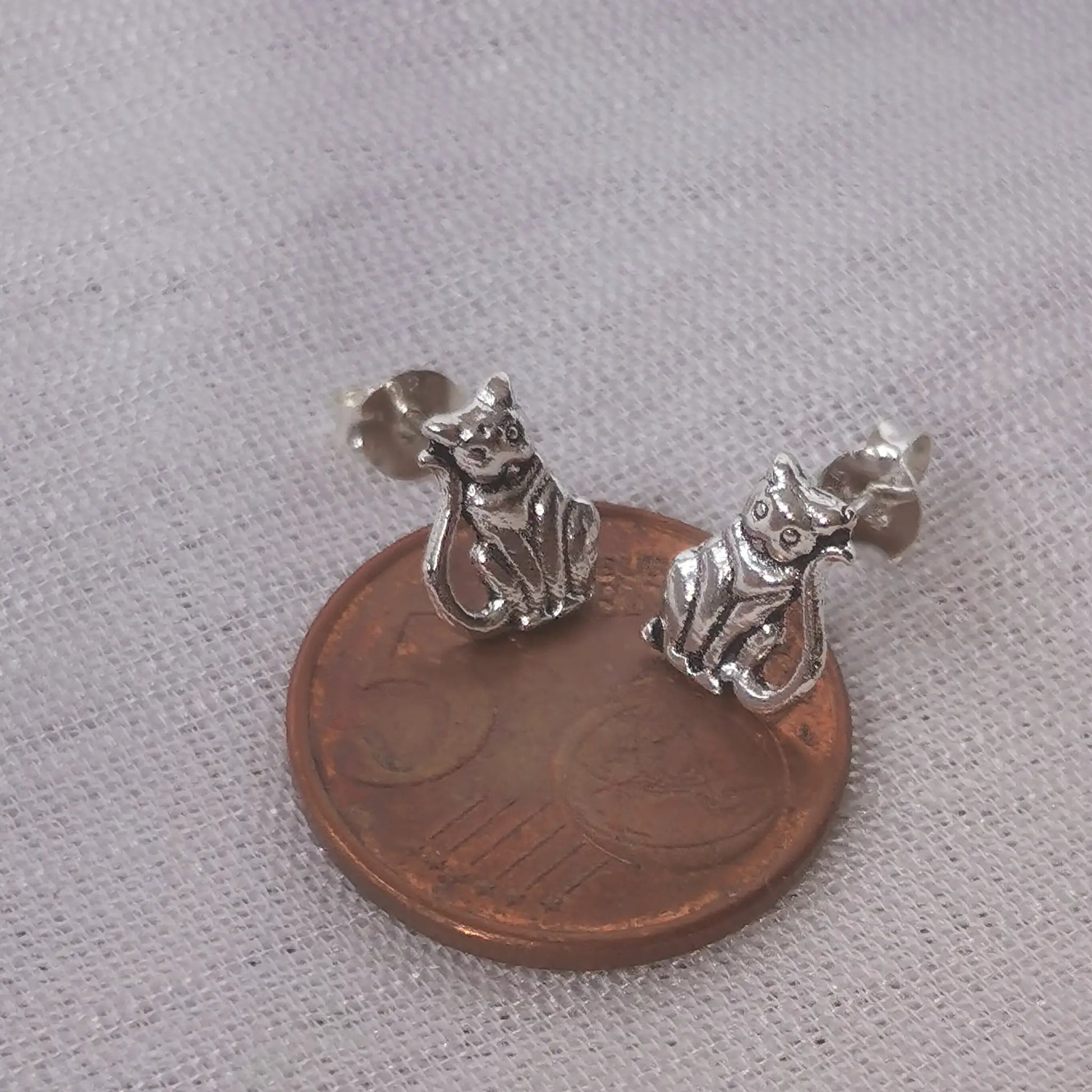 Größenvergleich: Die filigranen Katzen-Ohrringe aus 925 Silber platziert auf einer 5-Cent-Münze.