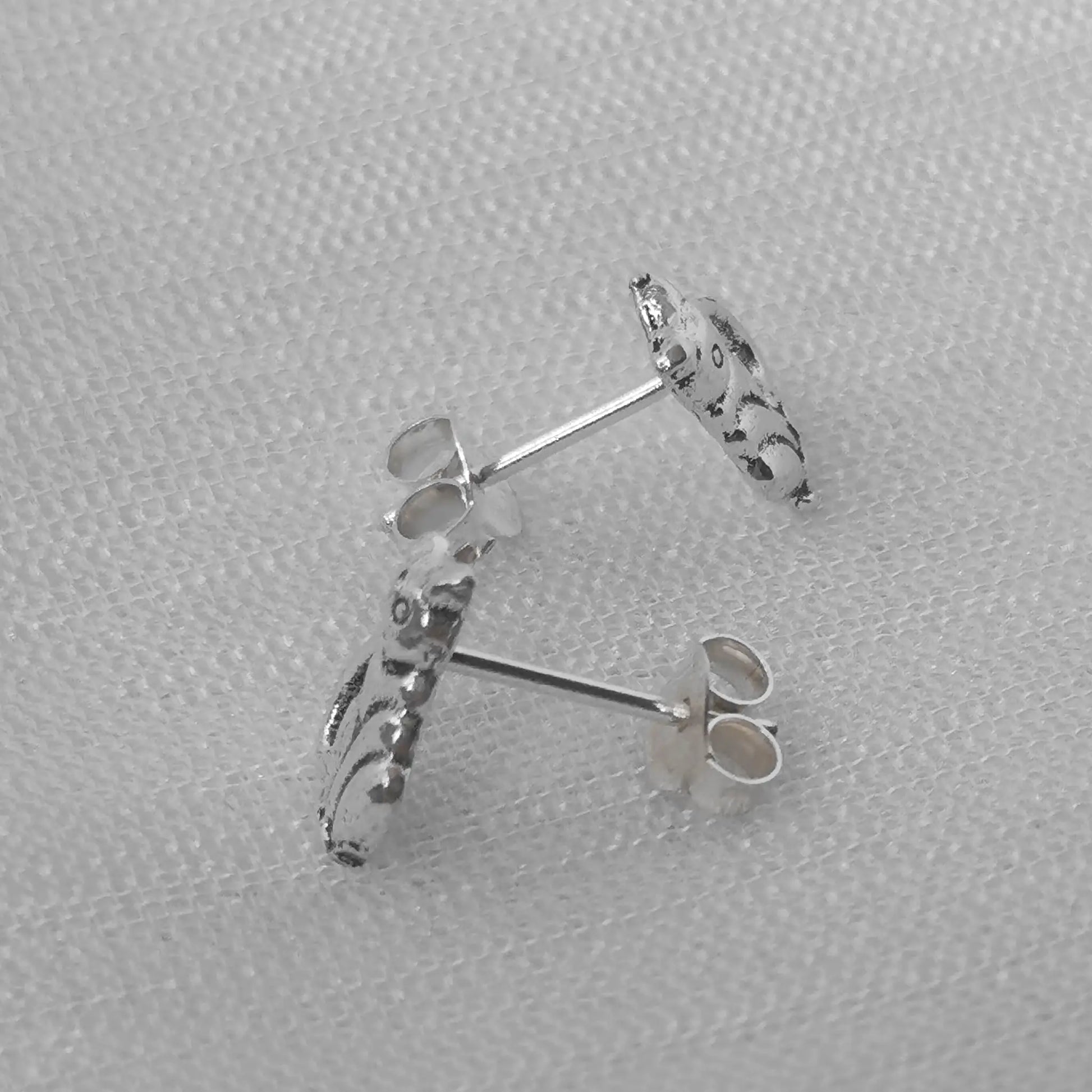 Seitenansicht der Katzen-Ohrstecker aus Silber, die das filigrane Profil und den geschwungenen Schwanz hervorhebt.